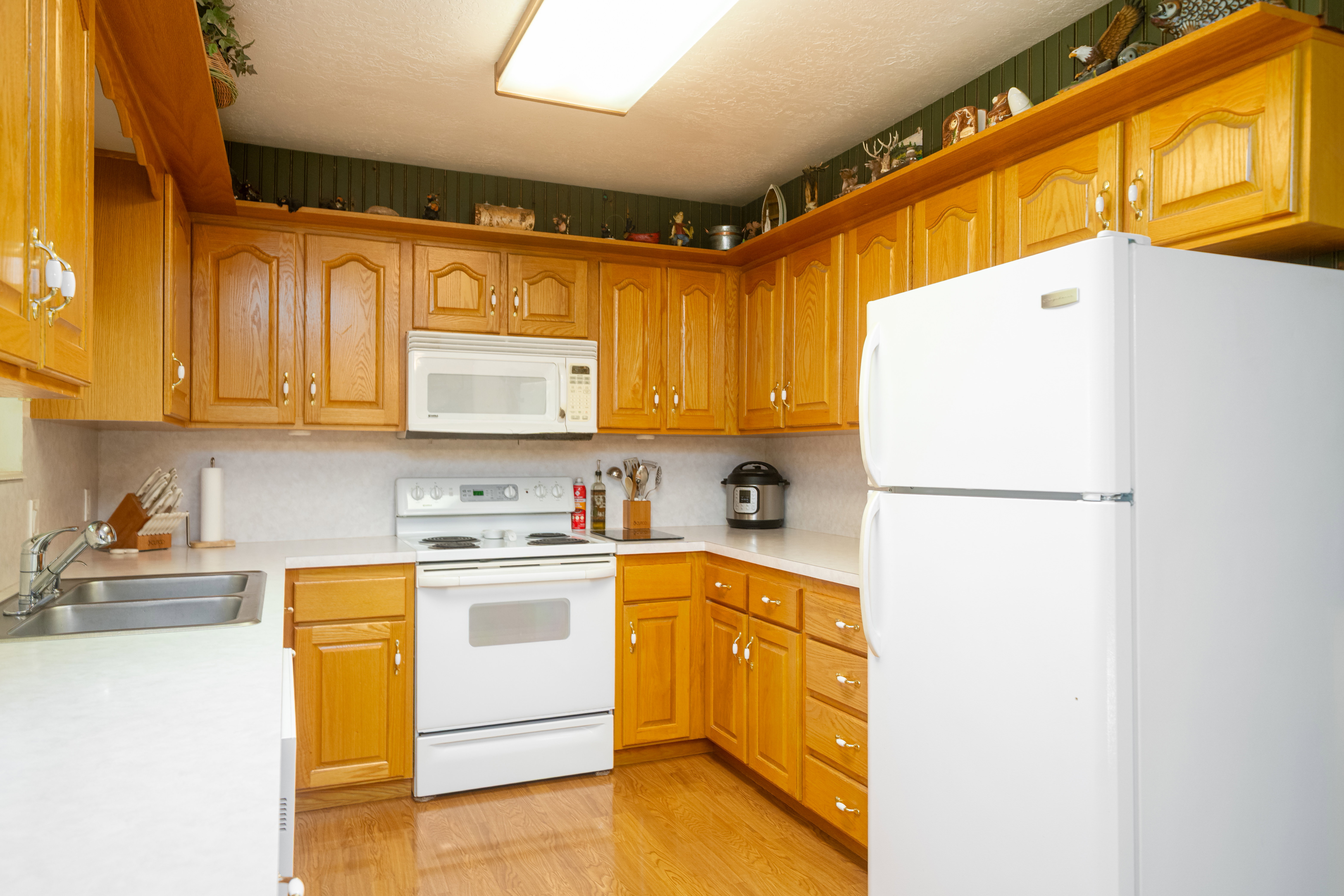 Kitchen featuring wood-finish cabinetry, white countertops, and white appliances