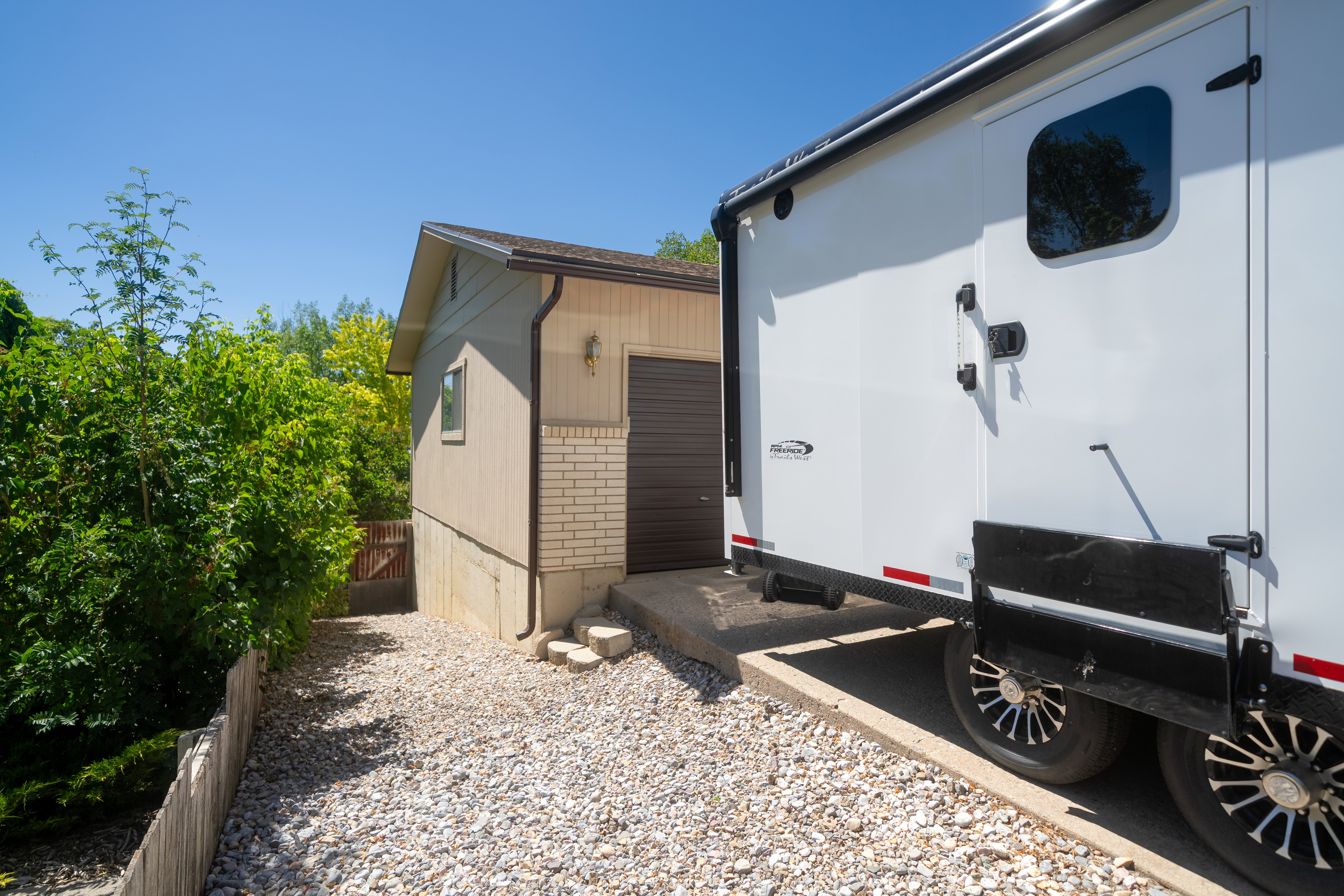 Detached accessory building featuring tan siding, brick veneer accent, and a brown overhead garage door
