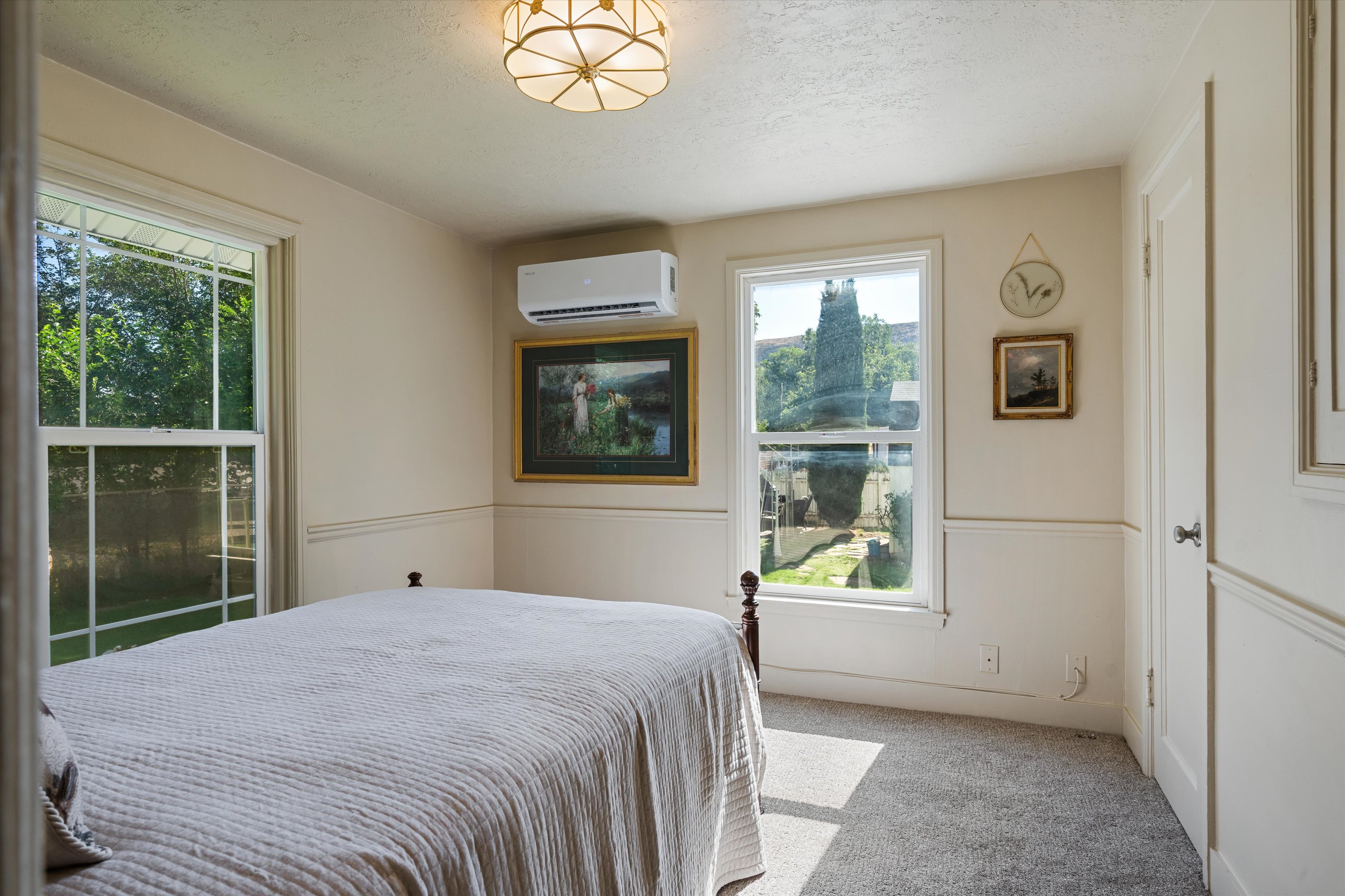 Room featuring neutral wall tones, wainscoting, carpet flooring, dual windows with ample natural light, and a built-in mini-split HVAC unit