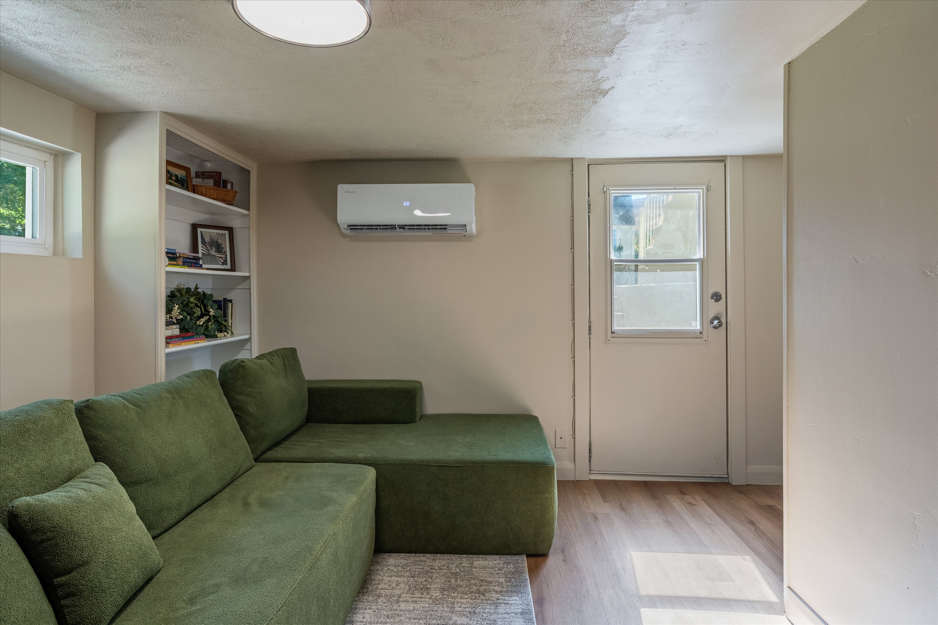 Room featuring wood-finish flooring, built-in shelving, a mini-split climate control system, and a door with an upper window