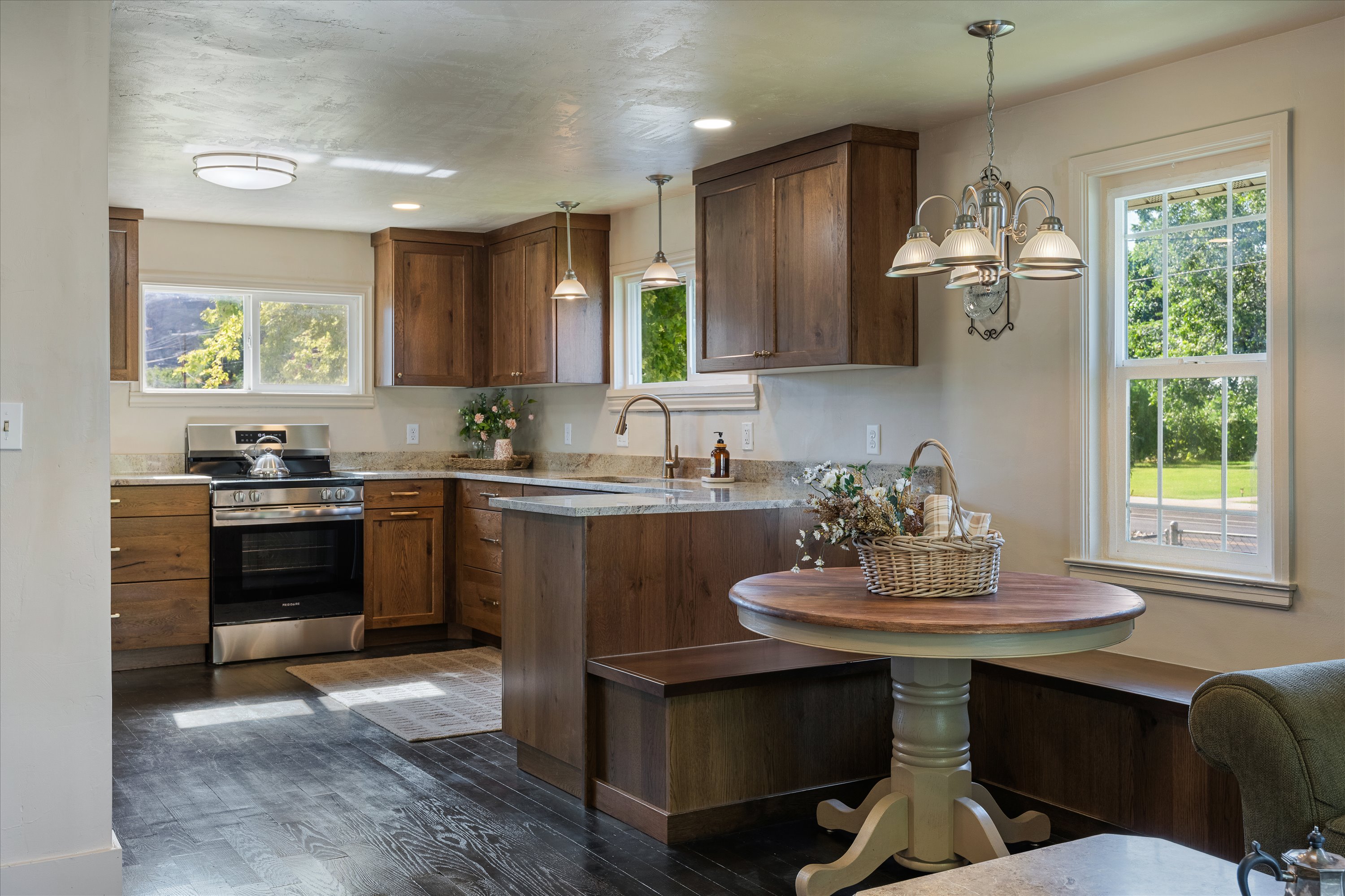 Kitchen featuring dark wood-finish flooring, stainless steel range, light-toned countertops, wood cabinetry, and a built-in bench seating arrangement