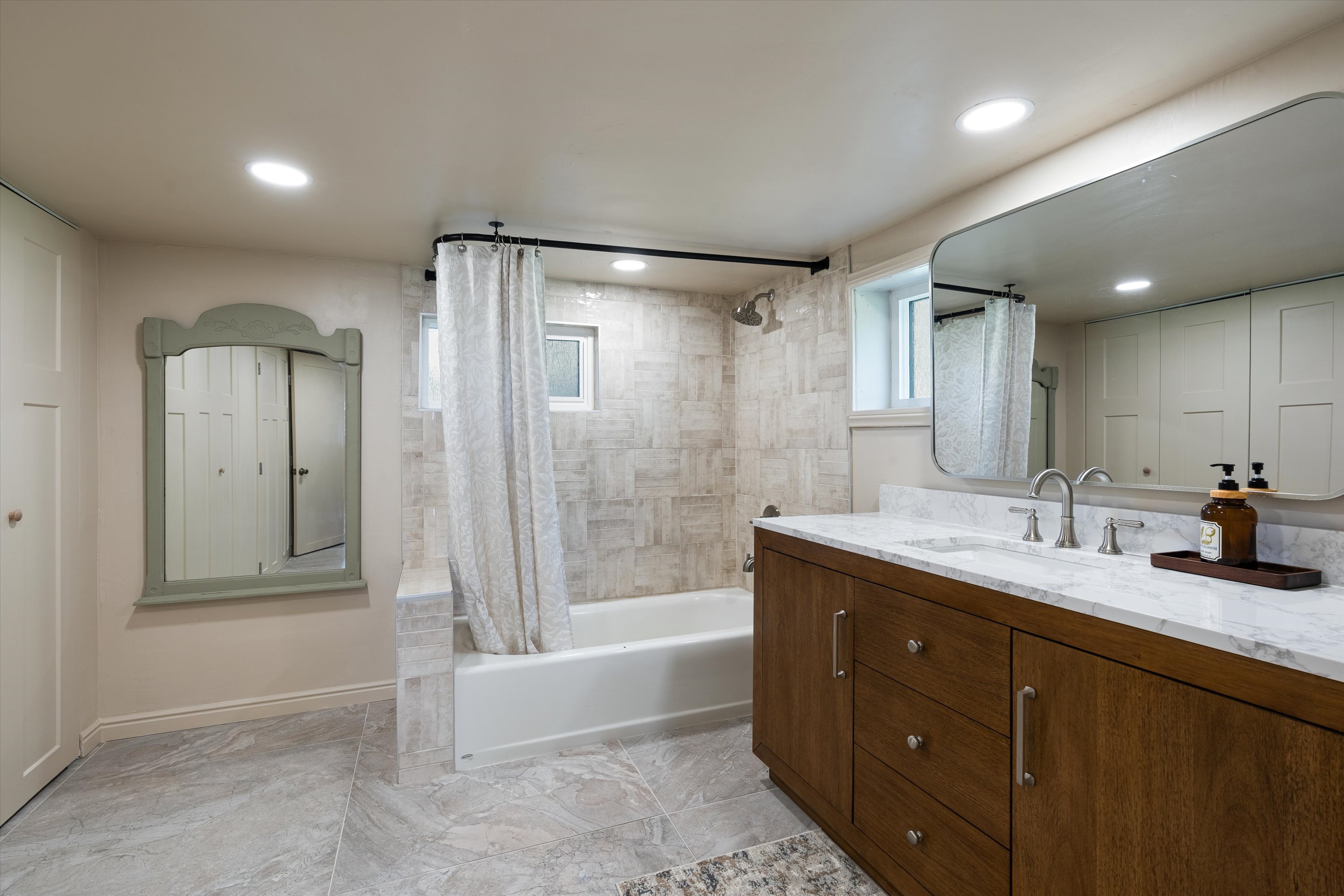 Bathroom featuring a wood-finish vanity with a light-colored countertop, an undermount sink, and a framed mirror