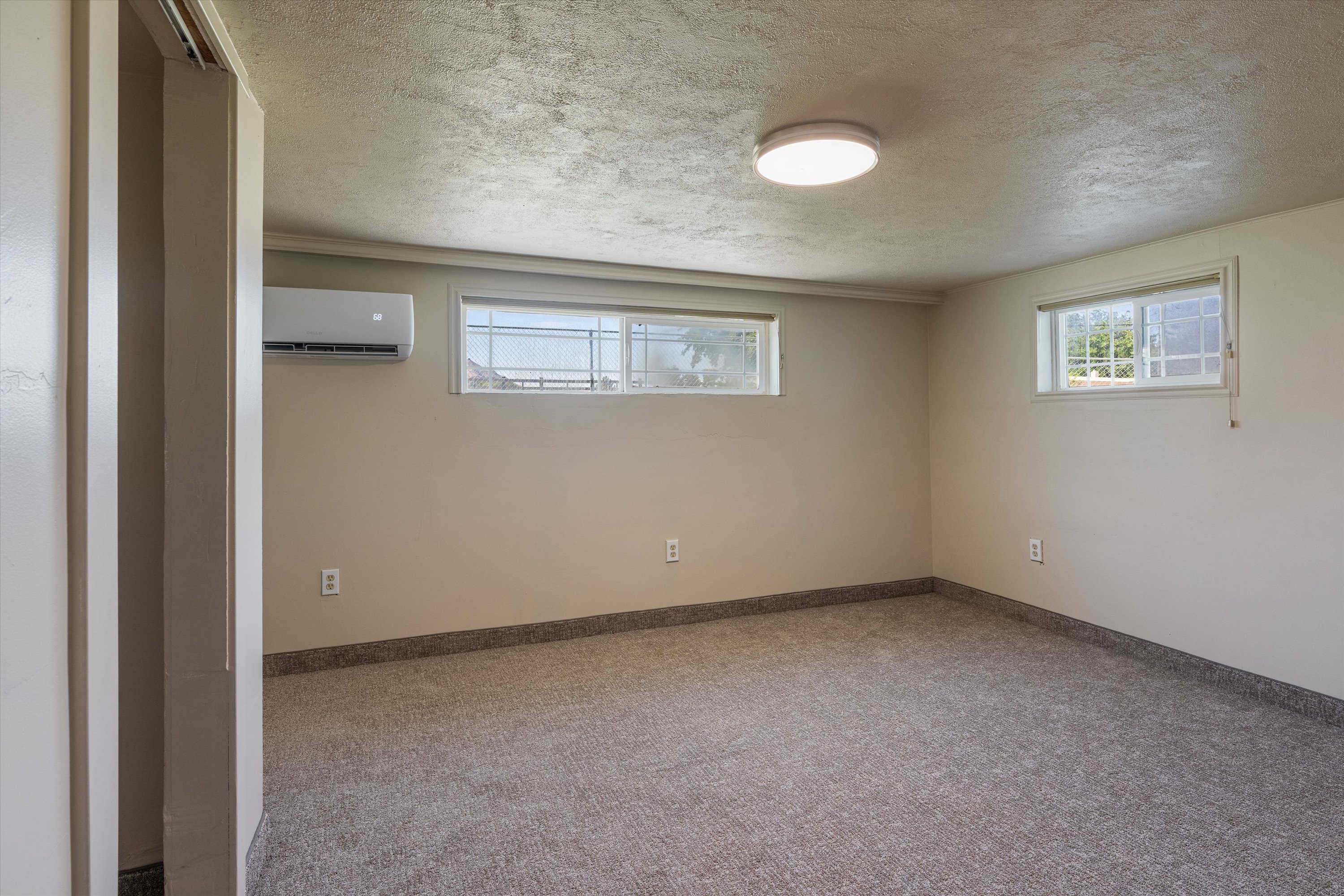 Carpeted room with neutral wall tones and a textured ceiling