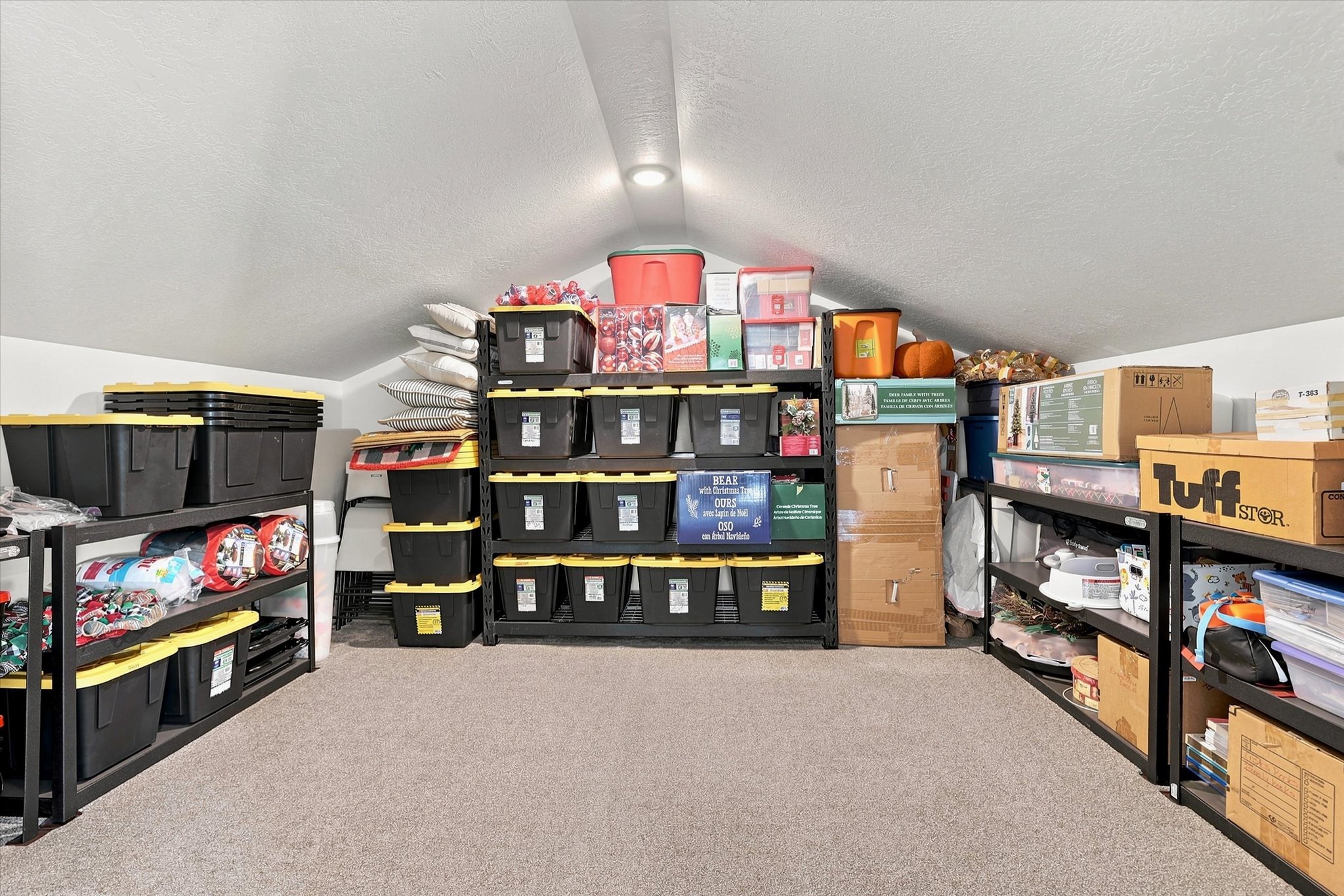 Carpeted attic storage space featuring sloped ceilings, recessed lighting, and built-in shelving