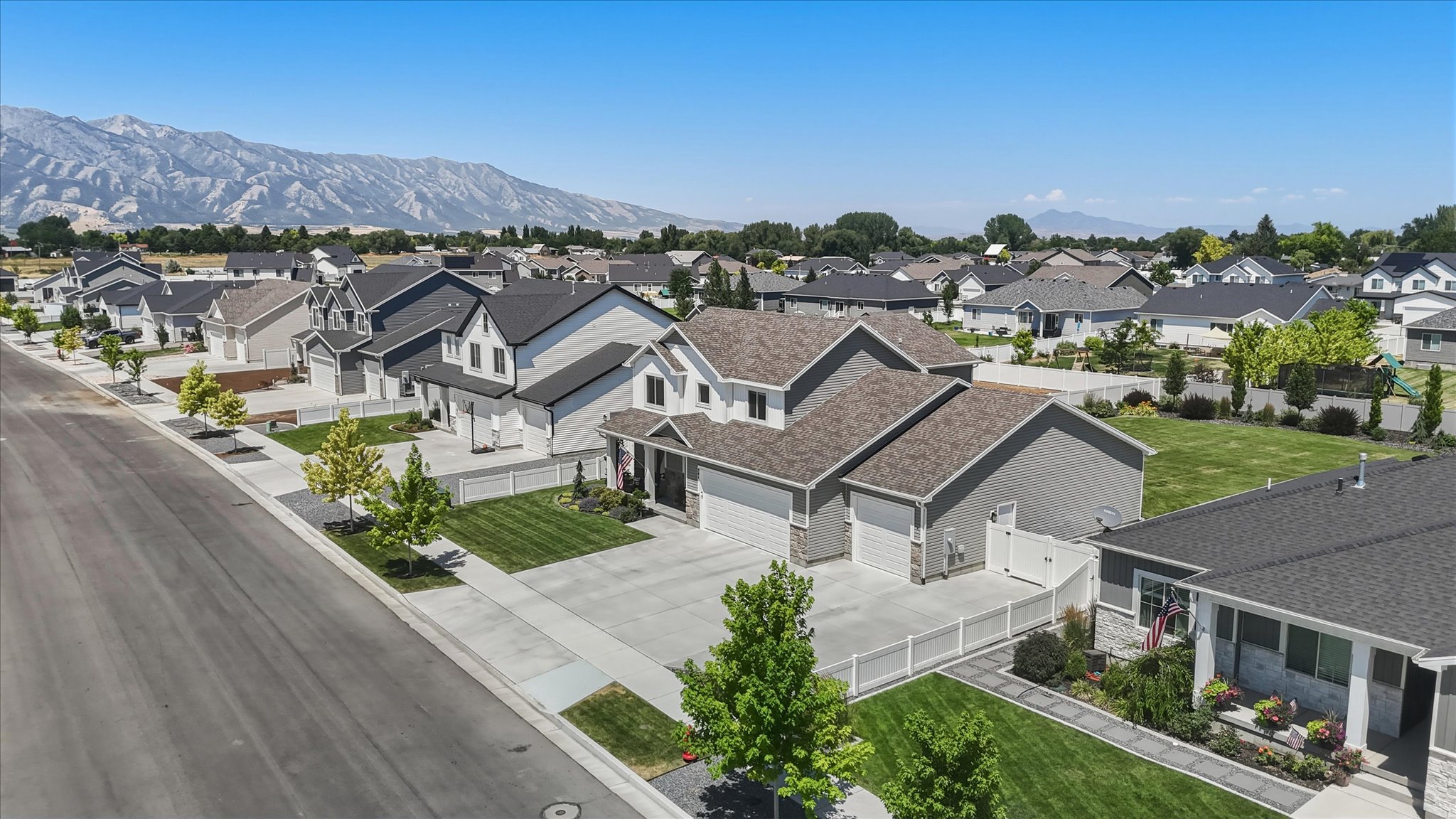 Well-maintained streetscape featuring multiple contemporary homes with dark shingle roofs, light-toned siding, and stone accents