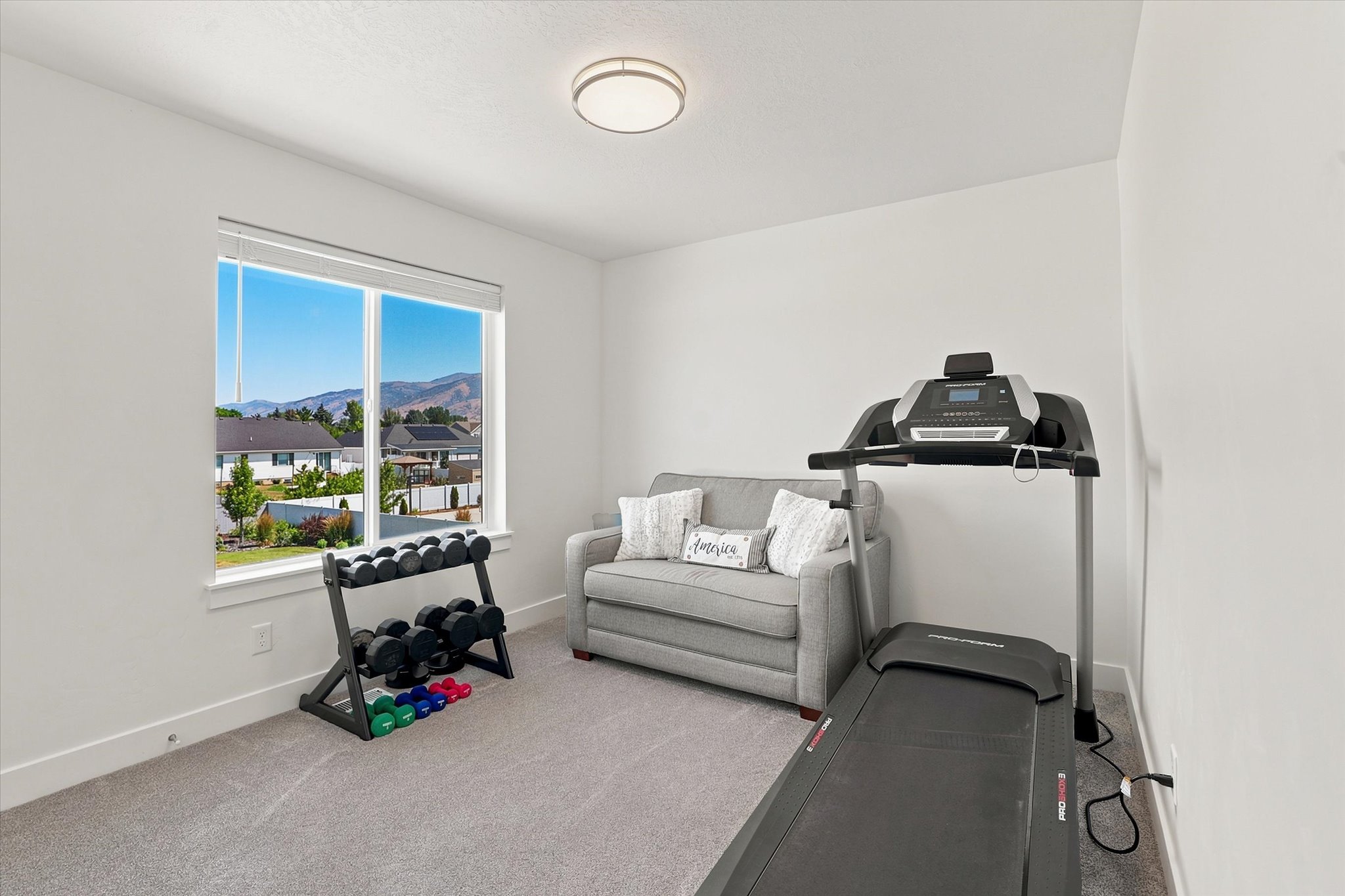 Bright room with a large picture window, showcasing mountain scenery and neighborhood properties