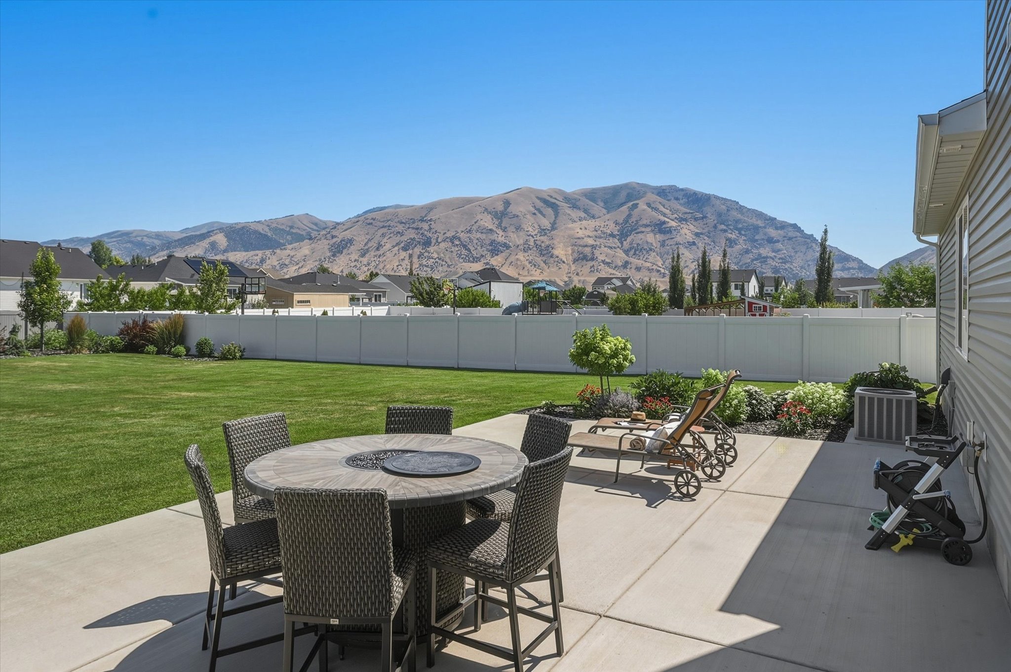 Expansive backyard featuring a concrete patio, a manicured lawn, and mature landscaping
