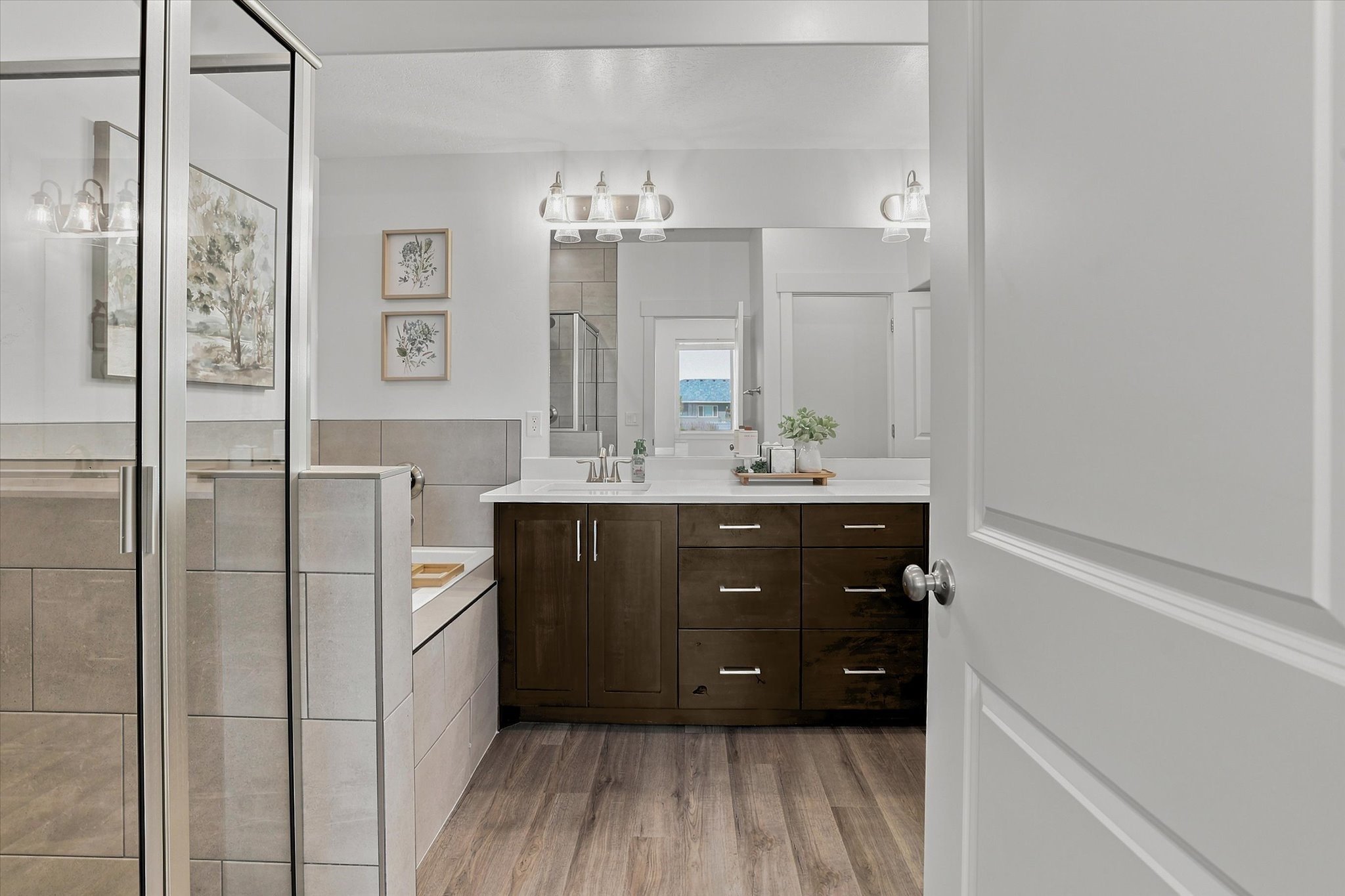 Contemporary bathroom featuring a spacious glass-enclosed shower, a separate soaking tub with tiled surround, and a double vanity with wood-finish cabinetry