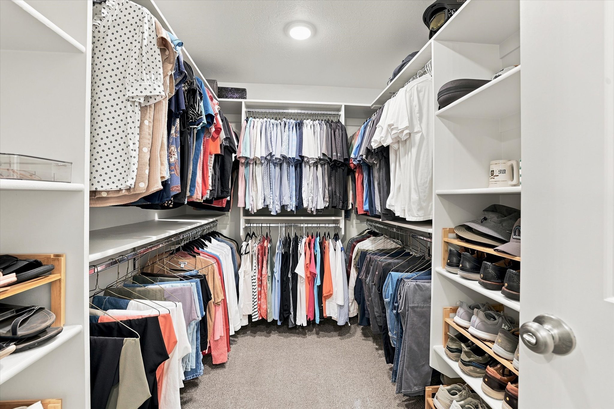 Walk-in closet featuring built-in white shelving, multiple hanging rods, recessed lighting, and soft gray carpeting