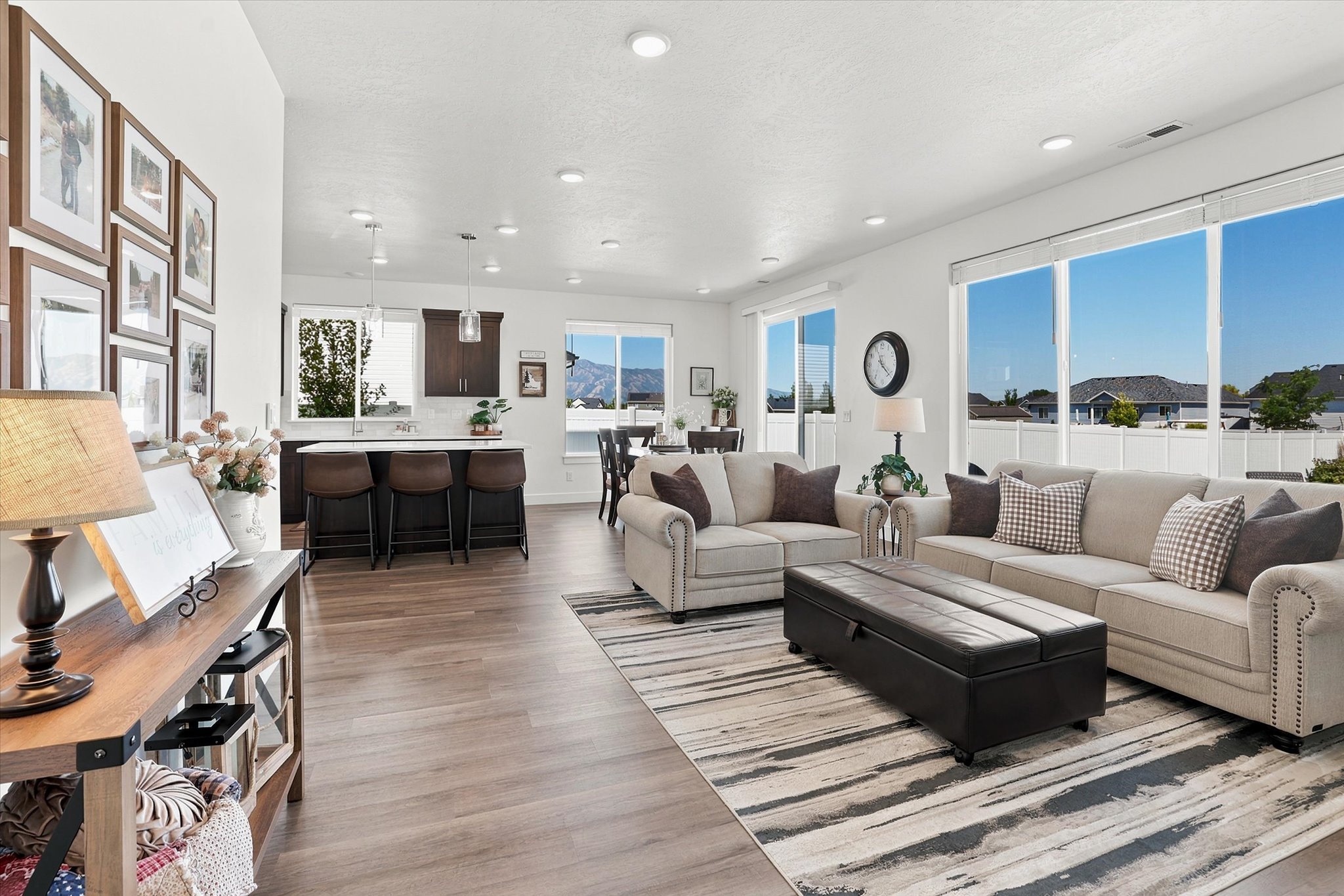 Open-concept interior featuring LVP wood-finish flooring throughout, recessed lighting, and large windows providing abundant natural light