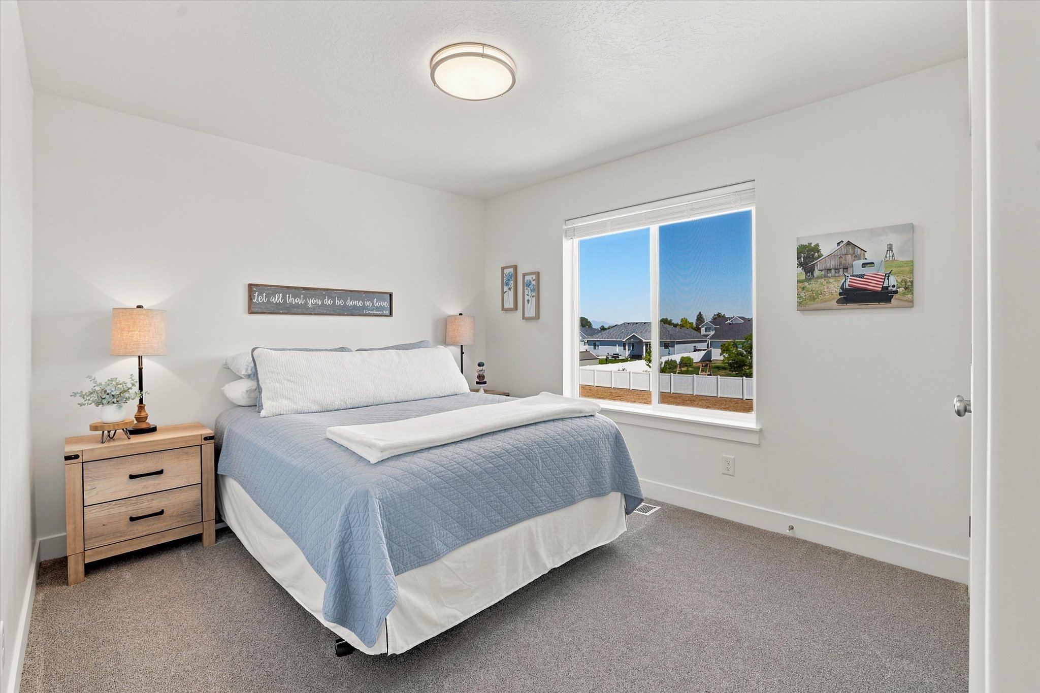 Bright bedroom featuring a large window, plush carpet flooring, and a flush-mount ceiling light fixture