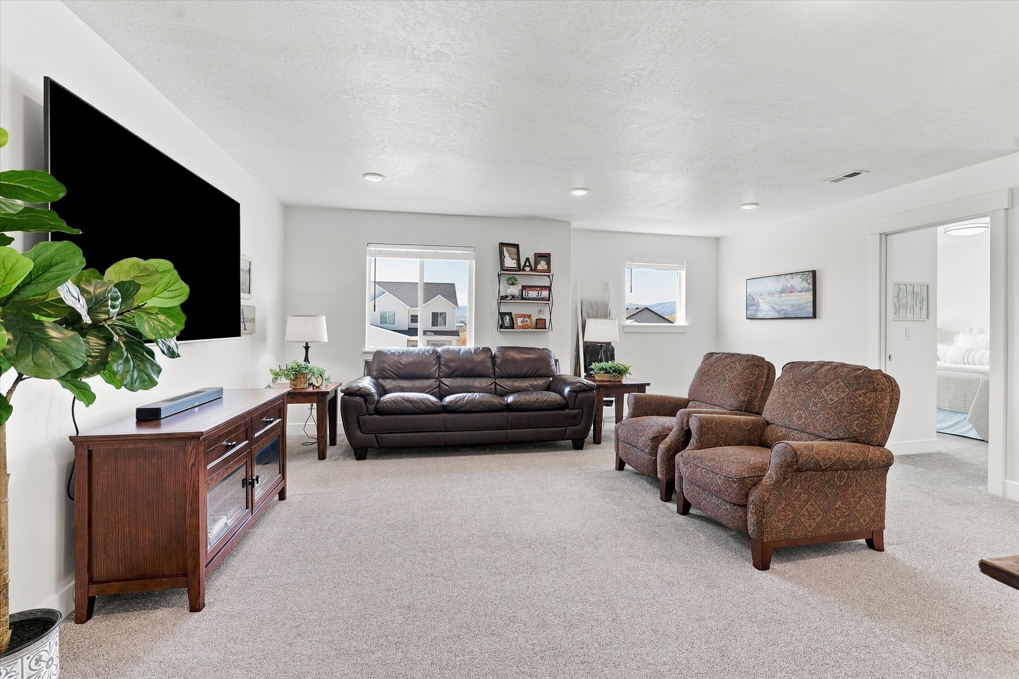 Spacious living area featuring light gray carpet flooring and white walls