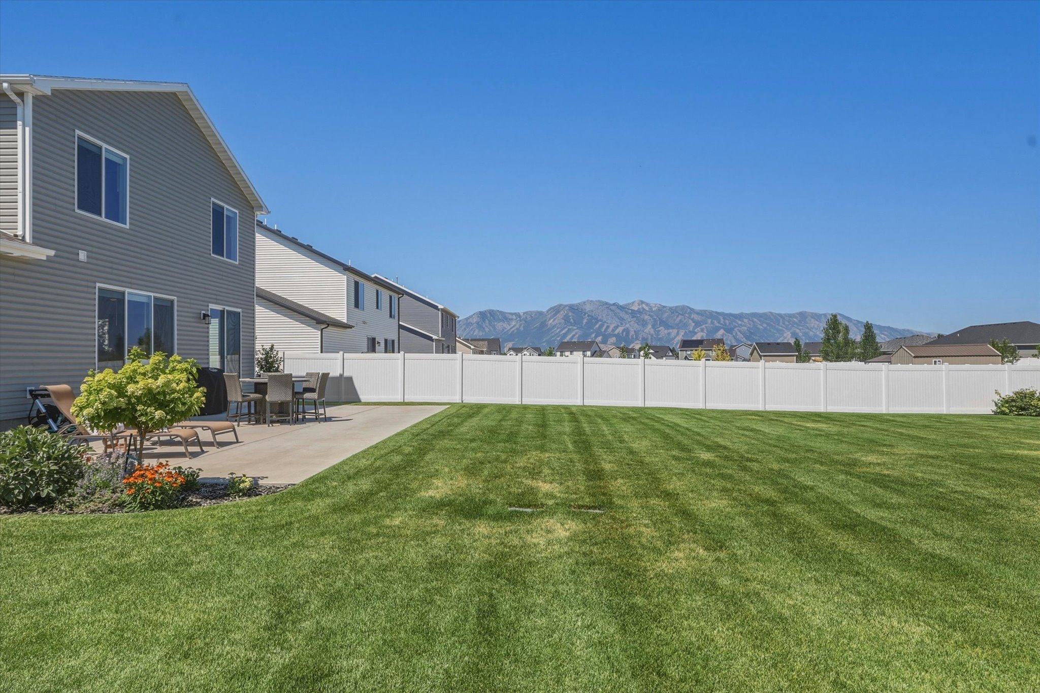 Expansive green lawn with a white privacy fence