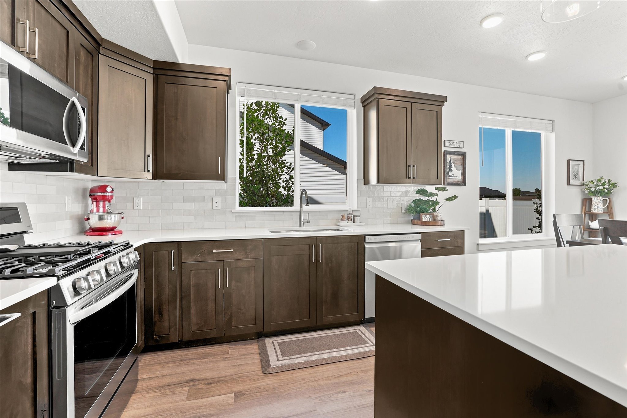 Kitchen featuring wood-finish cabinetry, stainless steel appliances, white subway tile backsplash, and light-colored countertops