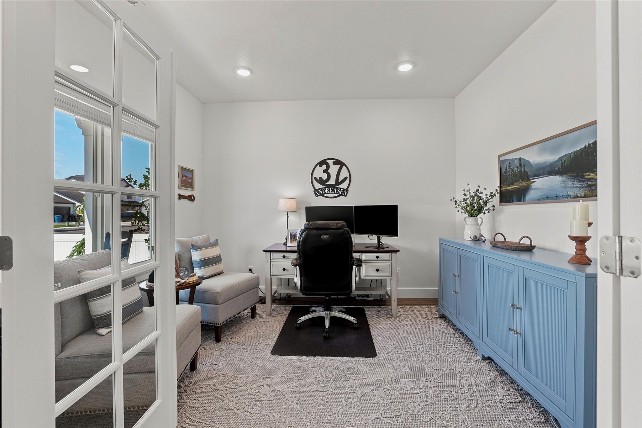 Bright room with recessed lighting and a light-colored area rug, featuring white walls and wood-finish flooring