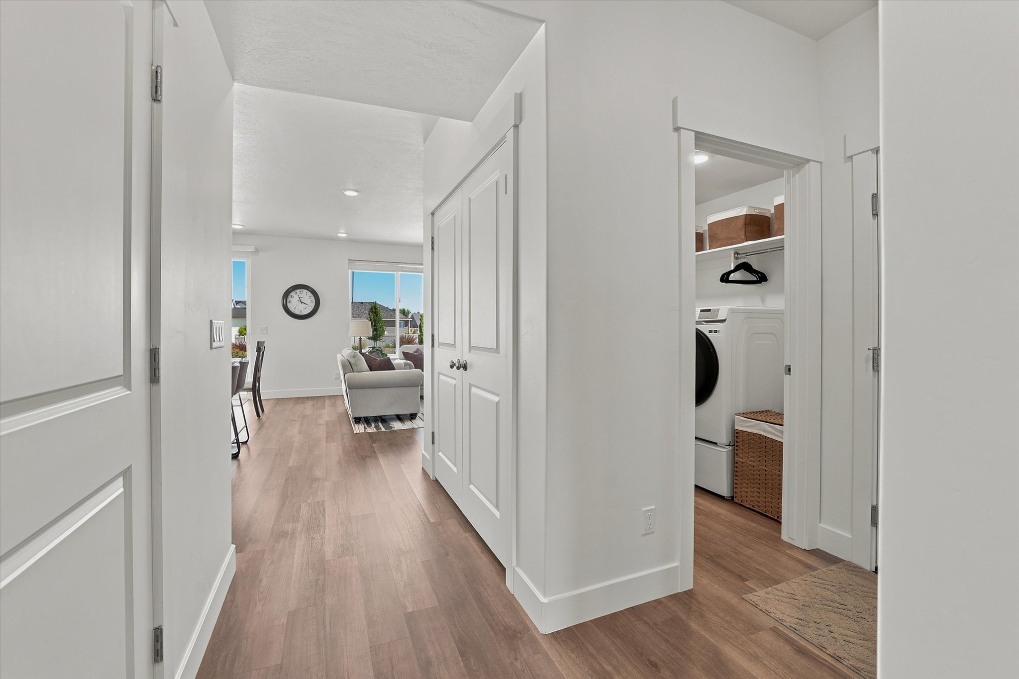 Hallway featuring wood-finish flooring, white walls, and bright overhead lighting
