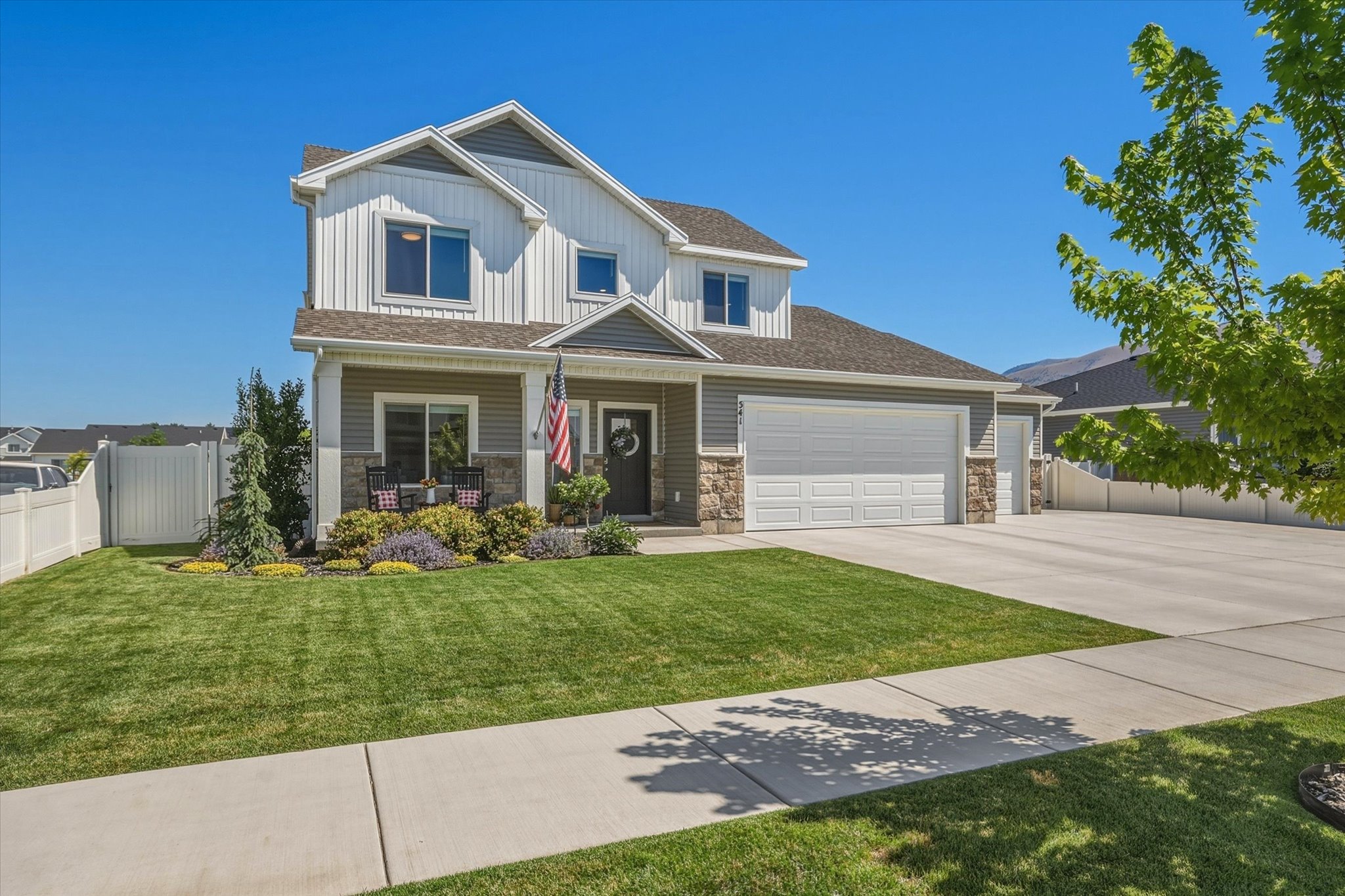 Two-story residence featuring a combination of horizontal and board-and-batten siding, stone accents, and a covered front porch