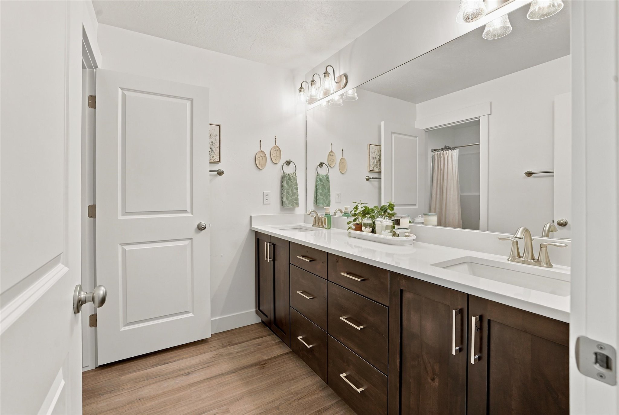 Dual sink vanity featuring dark wood-finish cabinetry, light countertops, and brushed nickel hardware