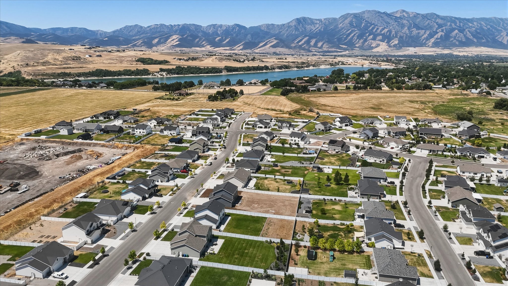 Aerial perspective showcasing a developed residential neighborhood with a distant body of water and mountain range backdrop