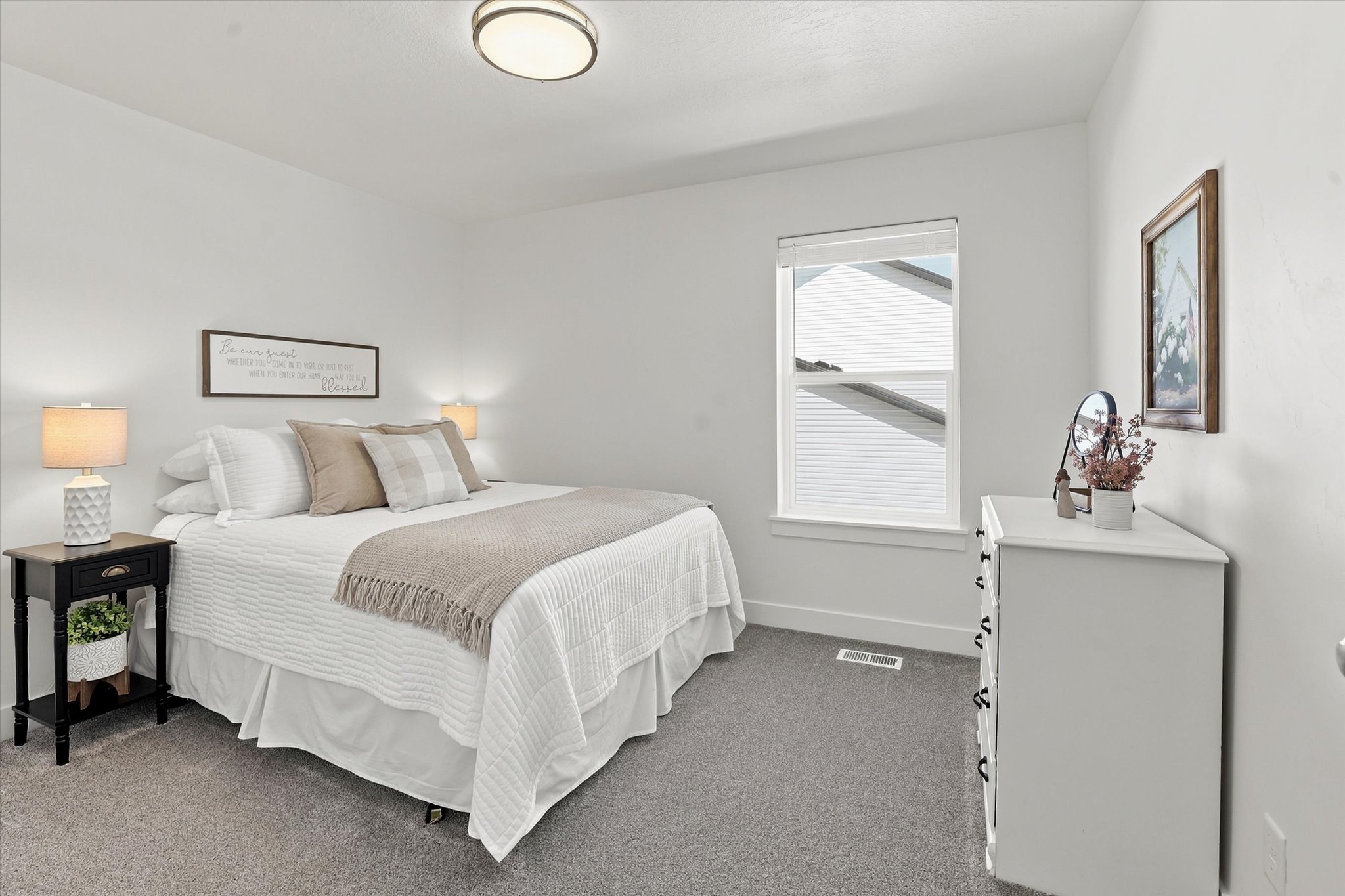 Bright bedroom featuring plush gray carpeting, white walls, and a contemporary ceiling light fixture