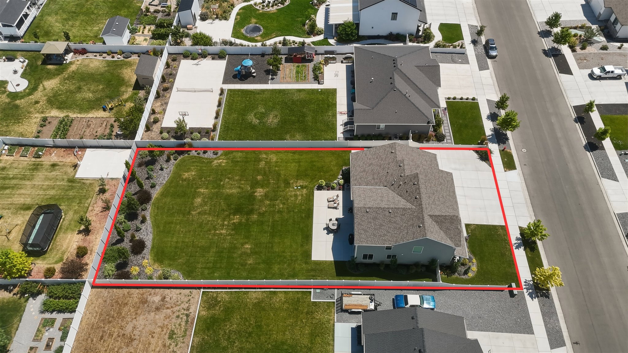 Expansive lot featuring a large grassy area, established landscaping, a multi-car driveway, and a residential structure with a shingle roof