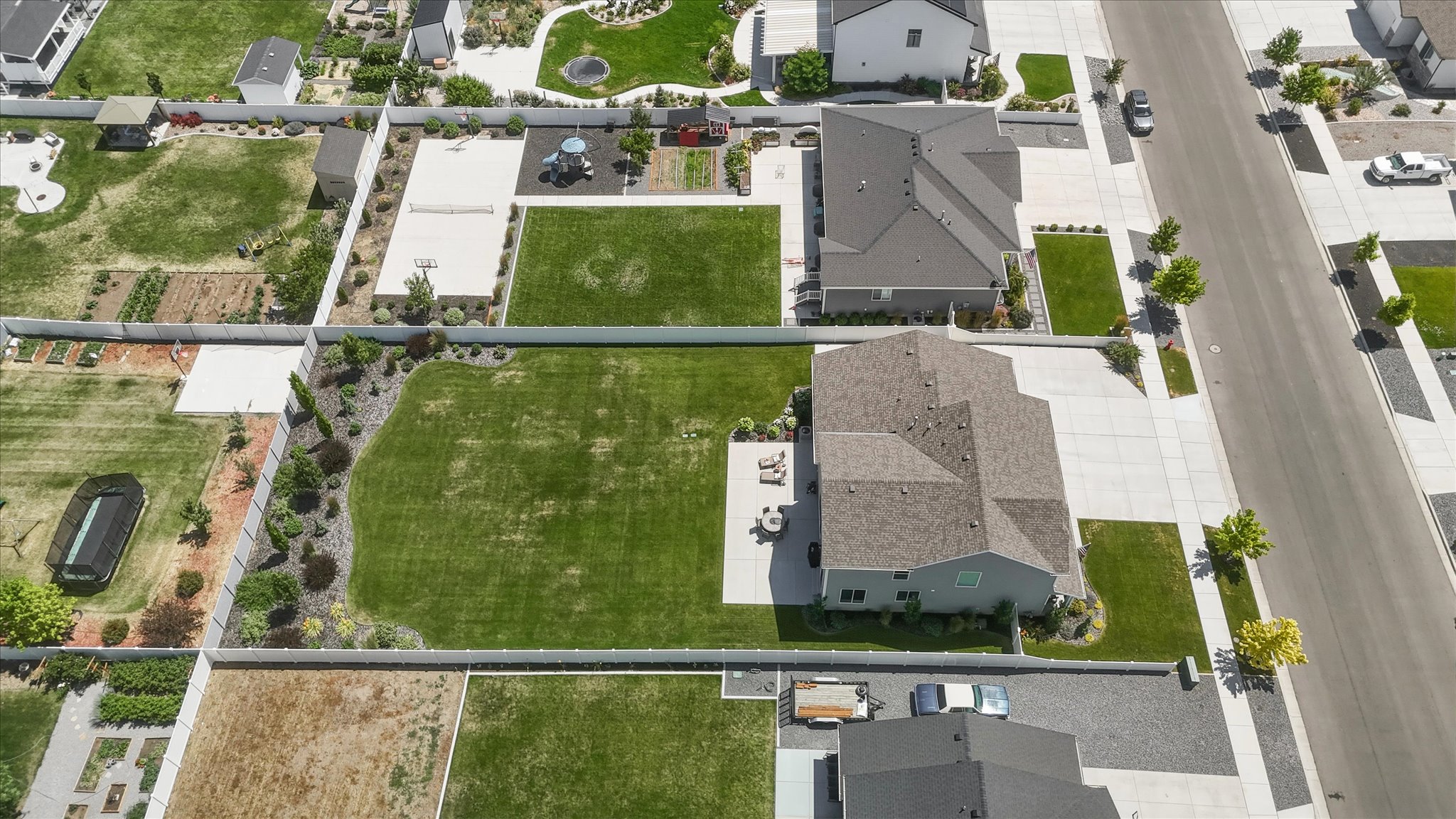 Expansive rear yard featuring a large patio, manicured lawn, and mature landscaping