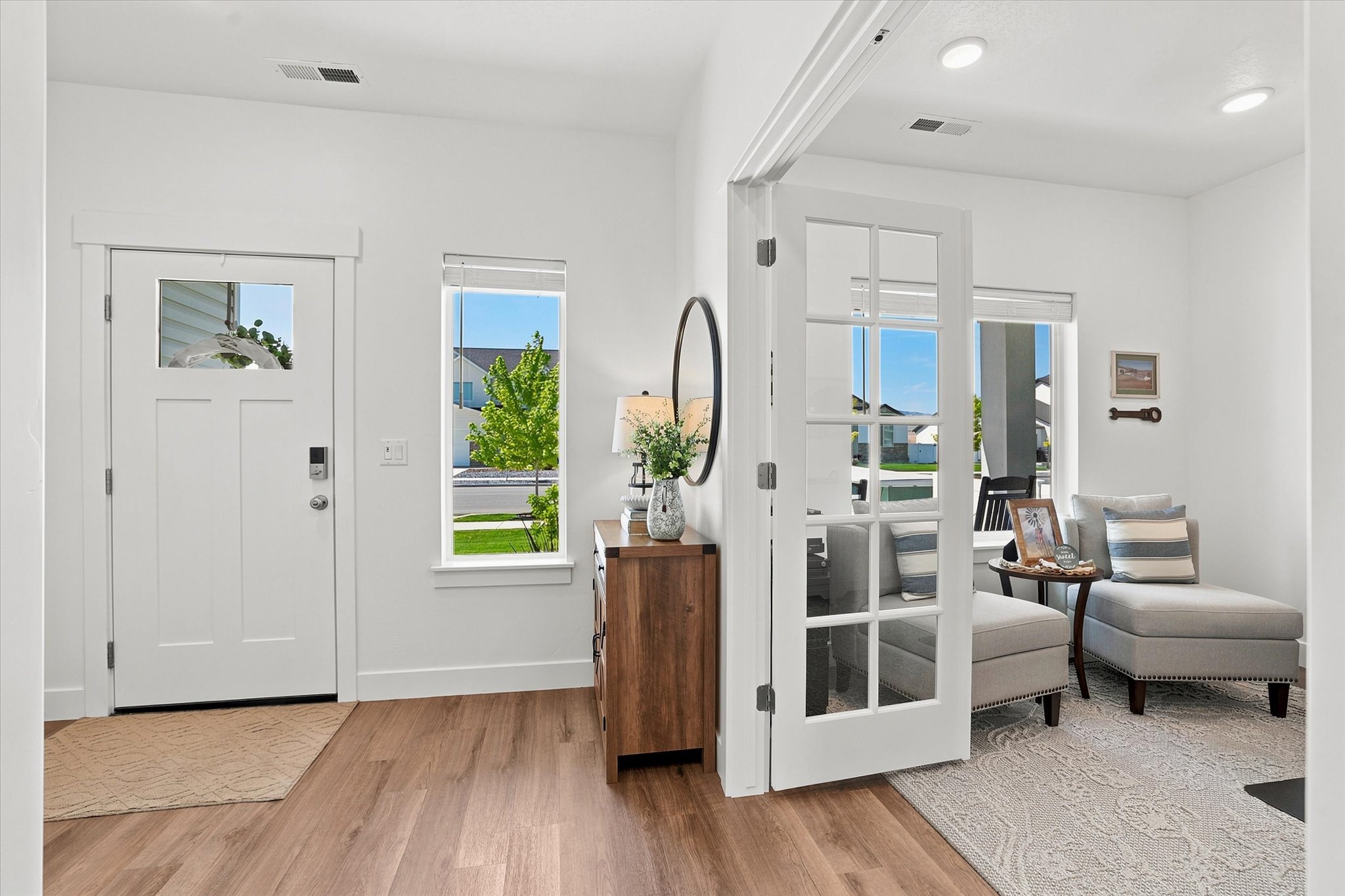 Entryway featuring LVP wood-finish flooring, a white front door with upper glass paneling, and a vertical window