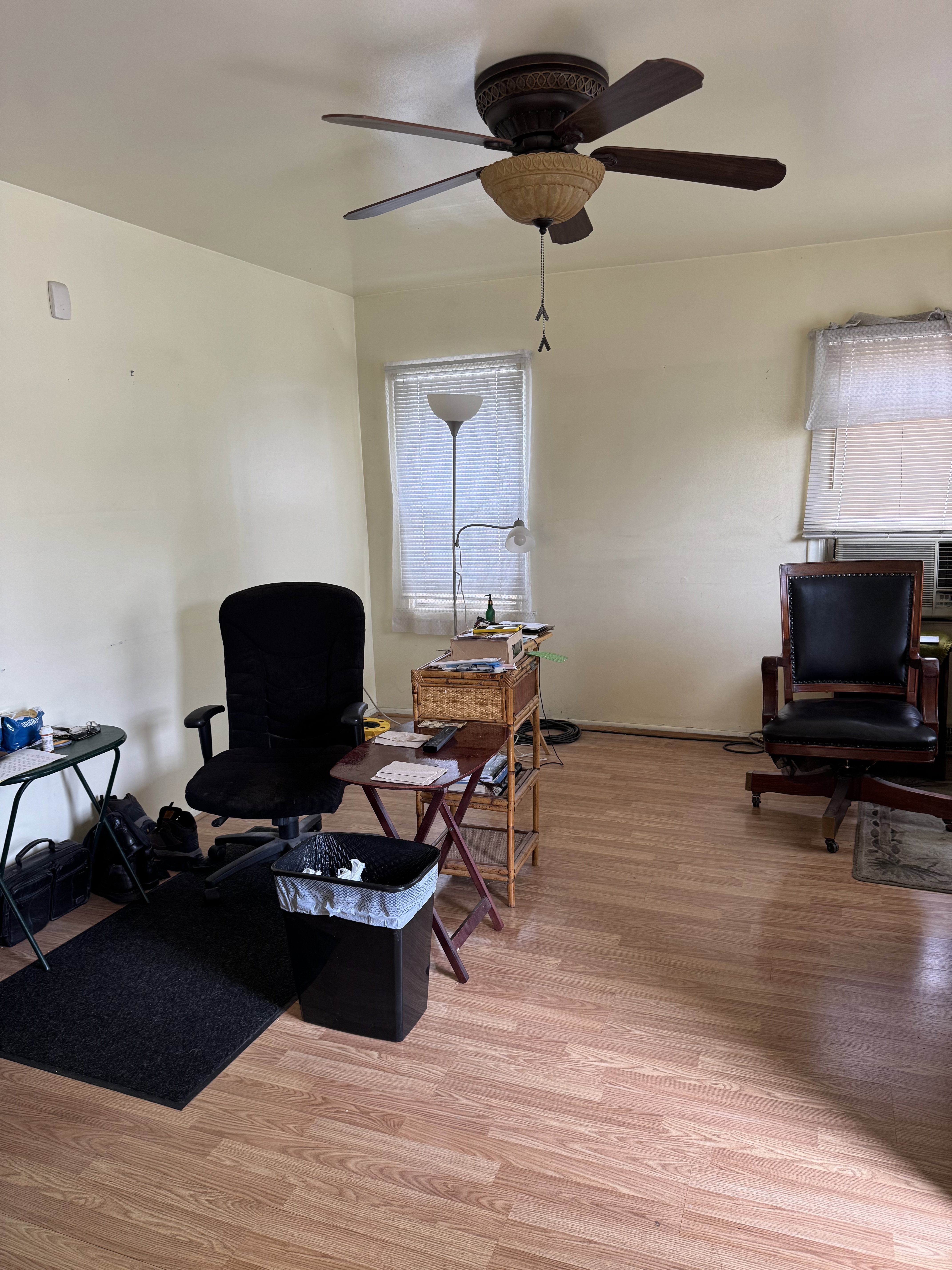 Room featuring wood-finish flooring, light-toned walls, and a ceiling fan with integrated lighting