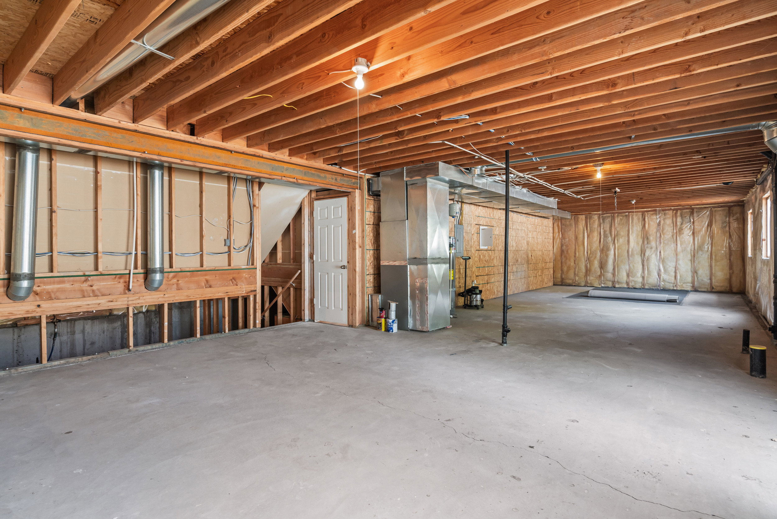 Unfinished basement featuring exposed wood joists, concrete flooring, and visible ductwork