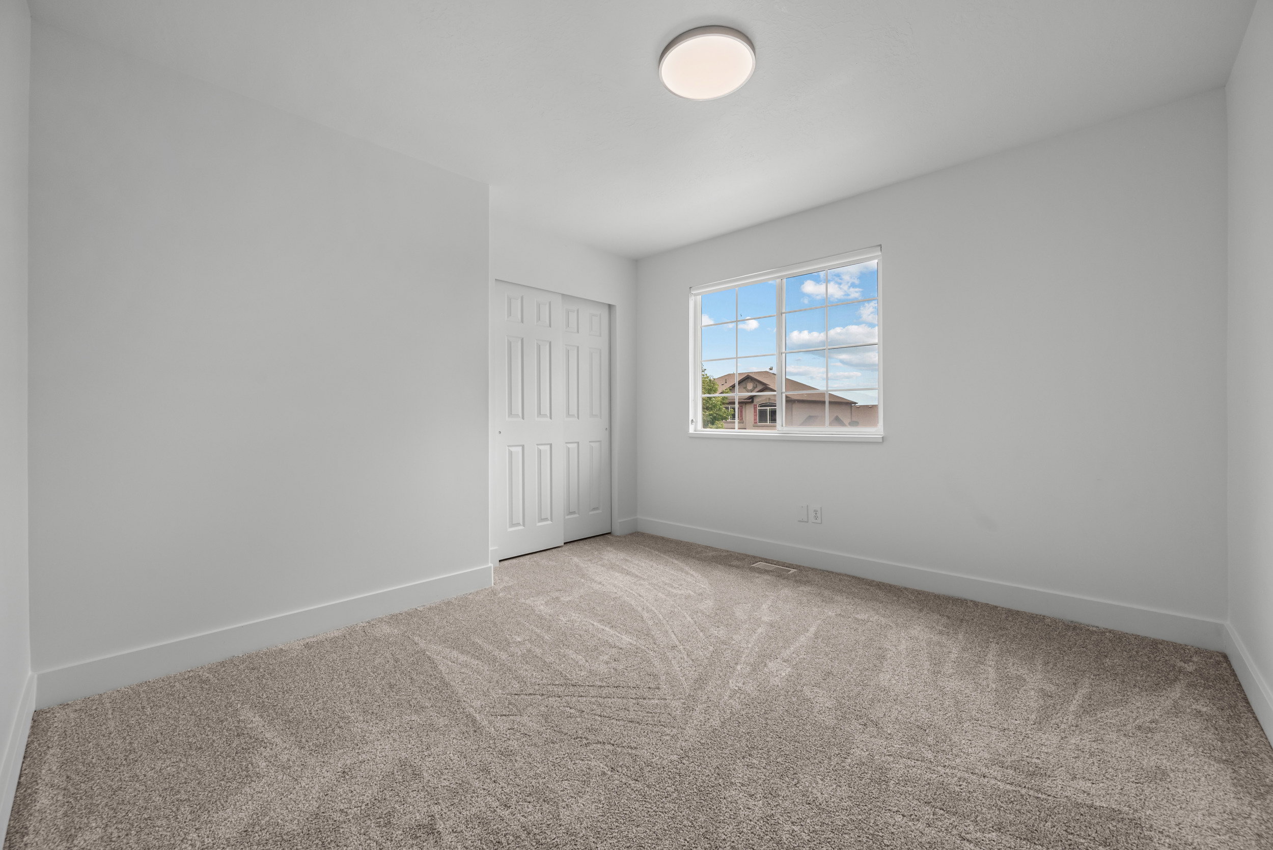 Interior room featuring light gray walls, plush gray patterned carpet, and white baseboards