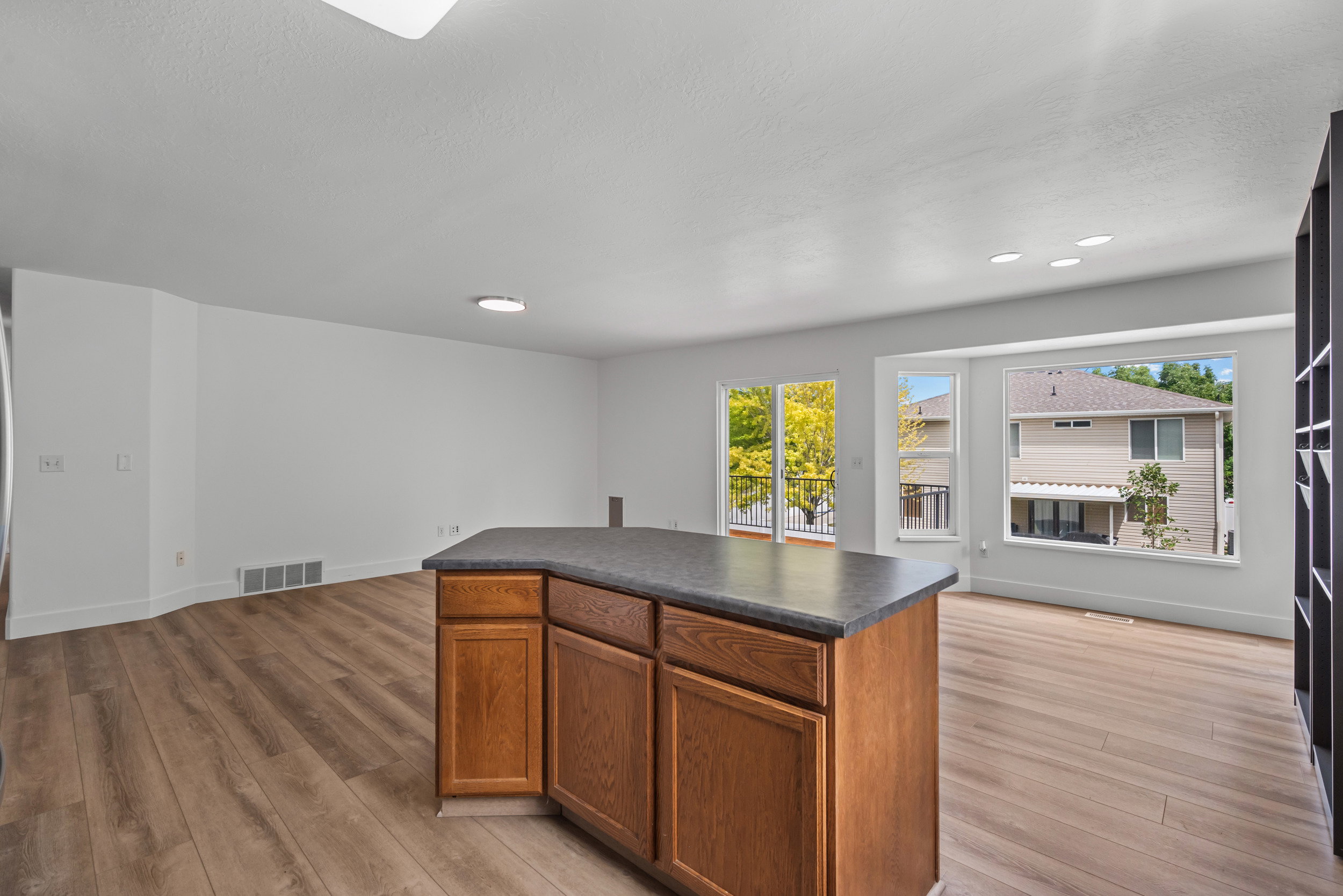 Kitchen island with wood-finish cabinetry and a dark countertop