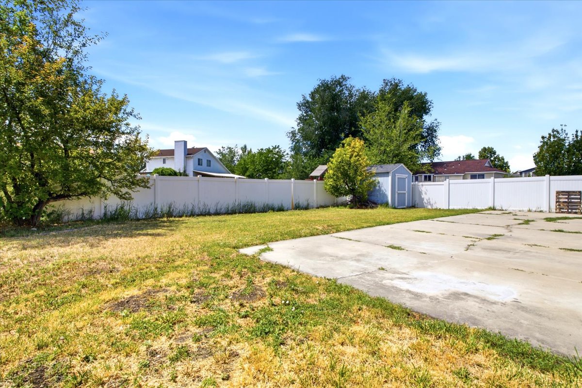 Expansive outdoor space featuring a concrete pad, a lawn area, and a white privacy fence