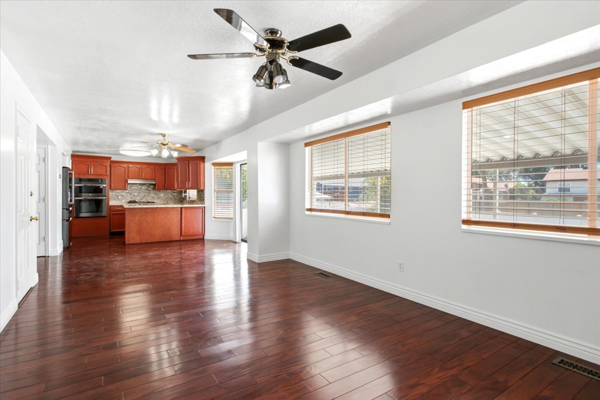 Expansive room featuring wood-finish flooring, two large windows with blinds, a ceiling fan, and recessed lighting