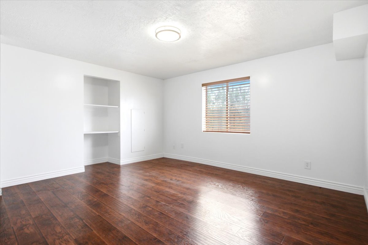 Room featuring rich wood-finish flooring, crisp white walls, and a recessed ceiling light