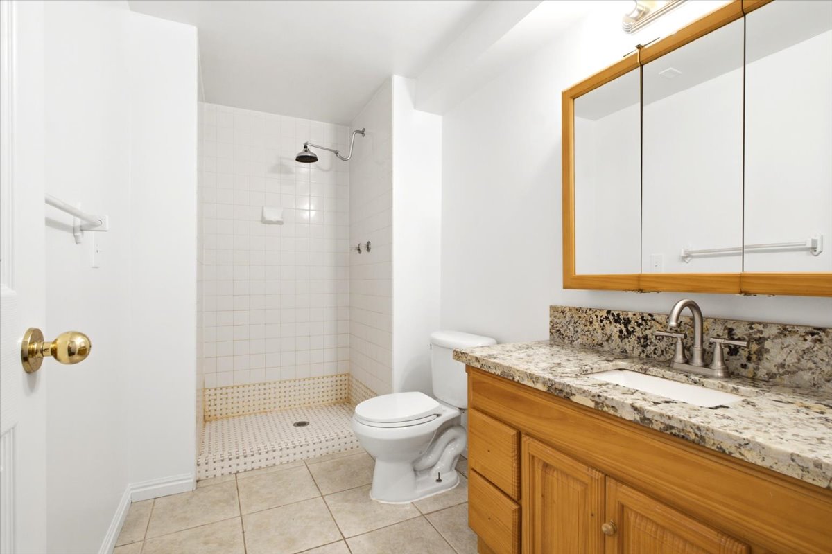 Bathroom featuring a wood vanity with a stone countertop, a rectangular undermount sink, and a mirrored medicine cabinet