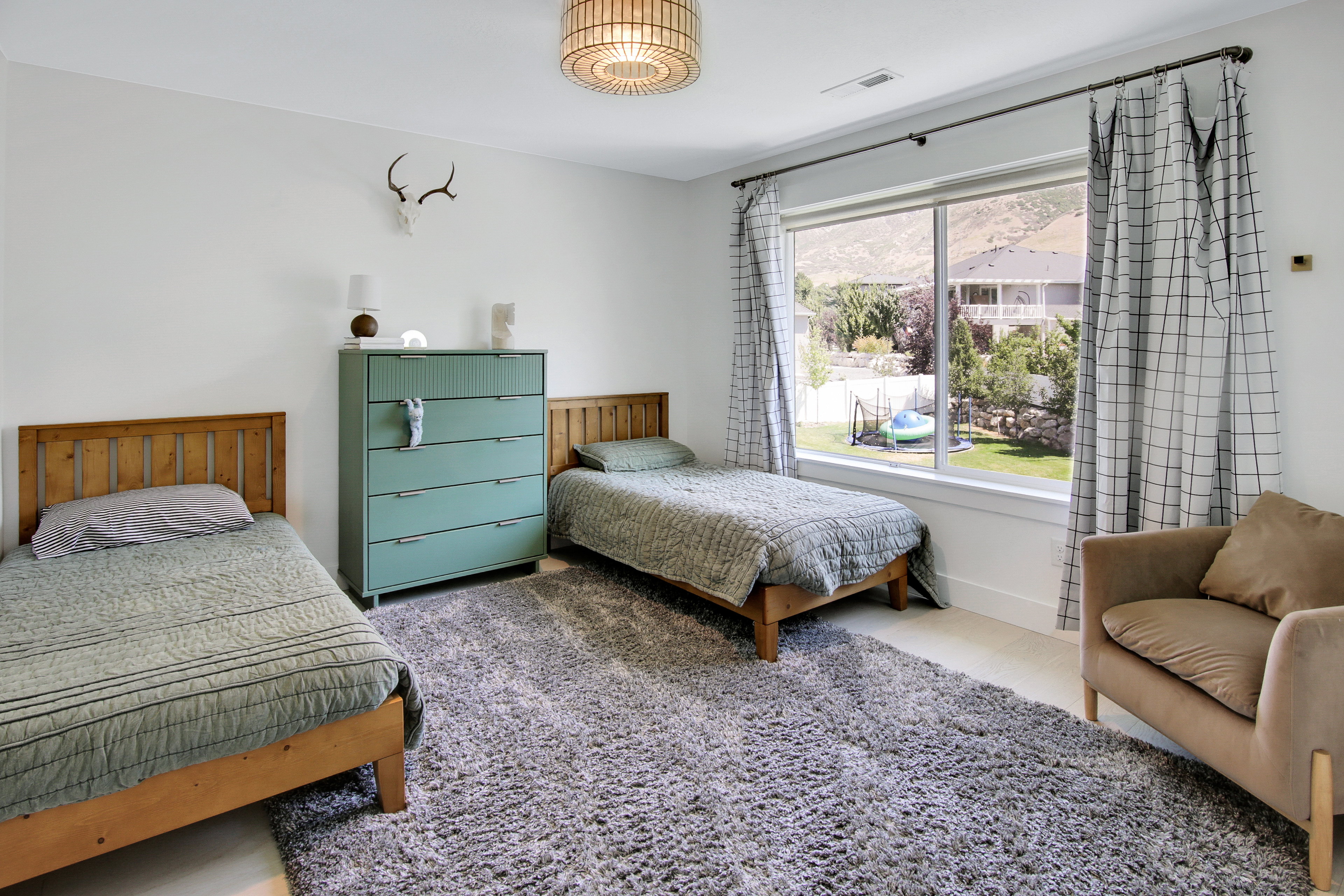 Spacious room featuring a large picture window, a textured area rug, and a modern ceiling light fixture