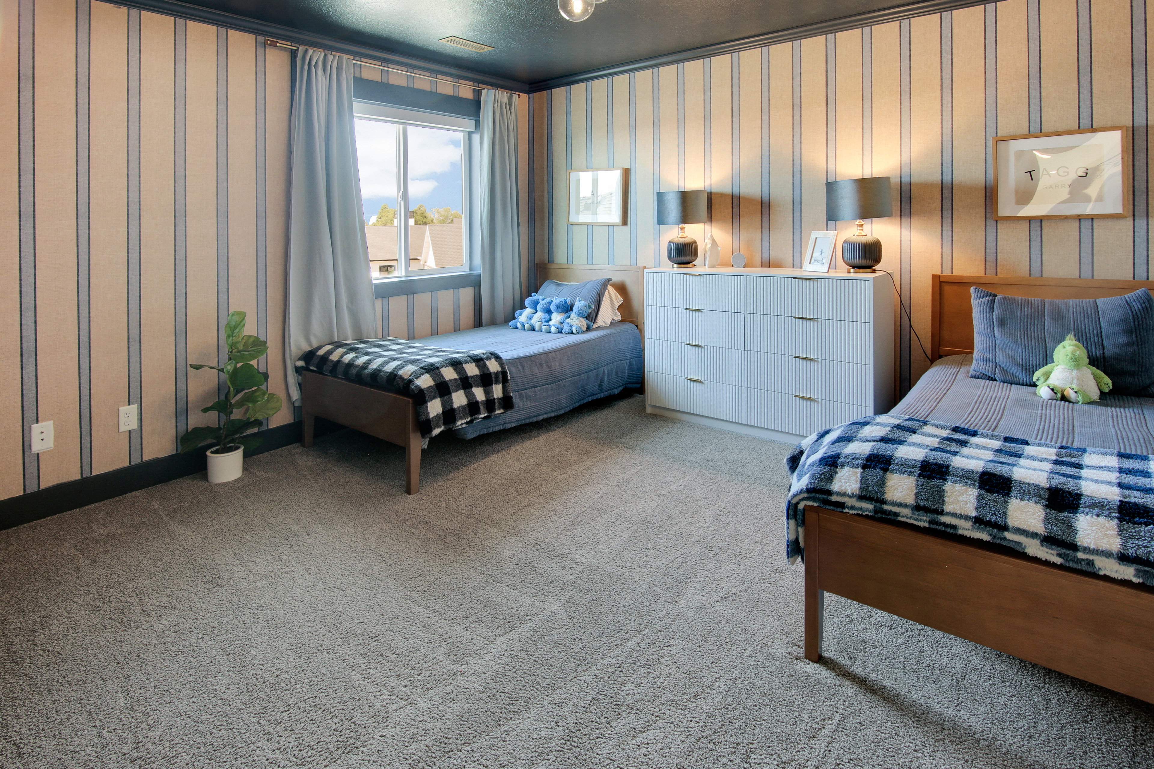 Carpeted room featuring striped wallpaper, a window with curtains, and dark painted trim
