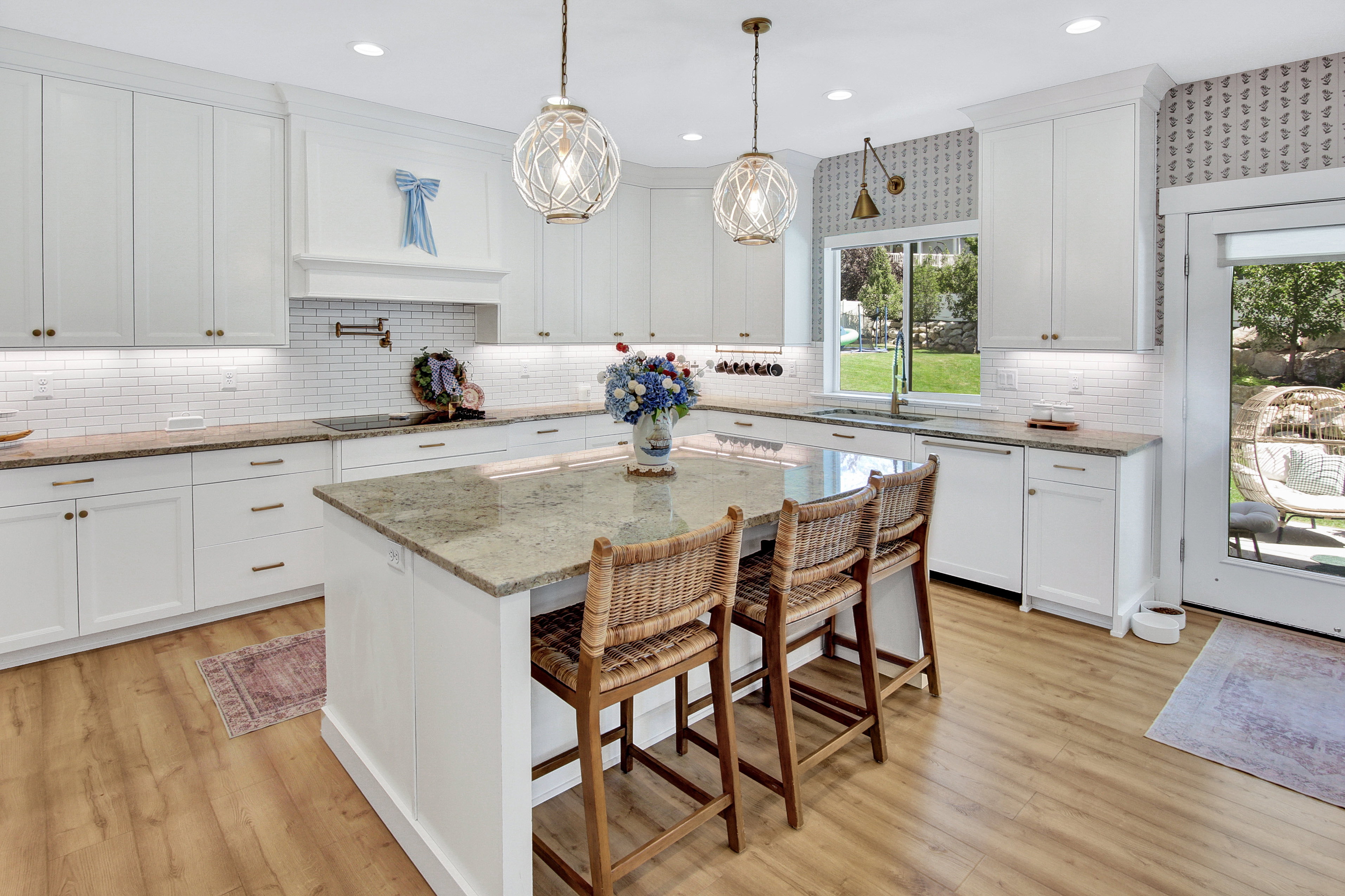 Spacious kitchen featuring an expansive island with a granite countertop, white shaker-style cabinetry, subway tile backsplash, recessed lighting, and wood-finish flooring