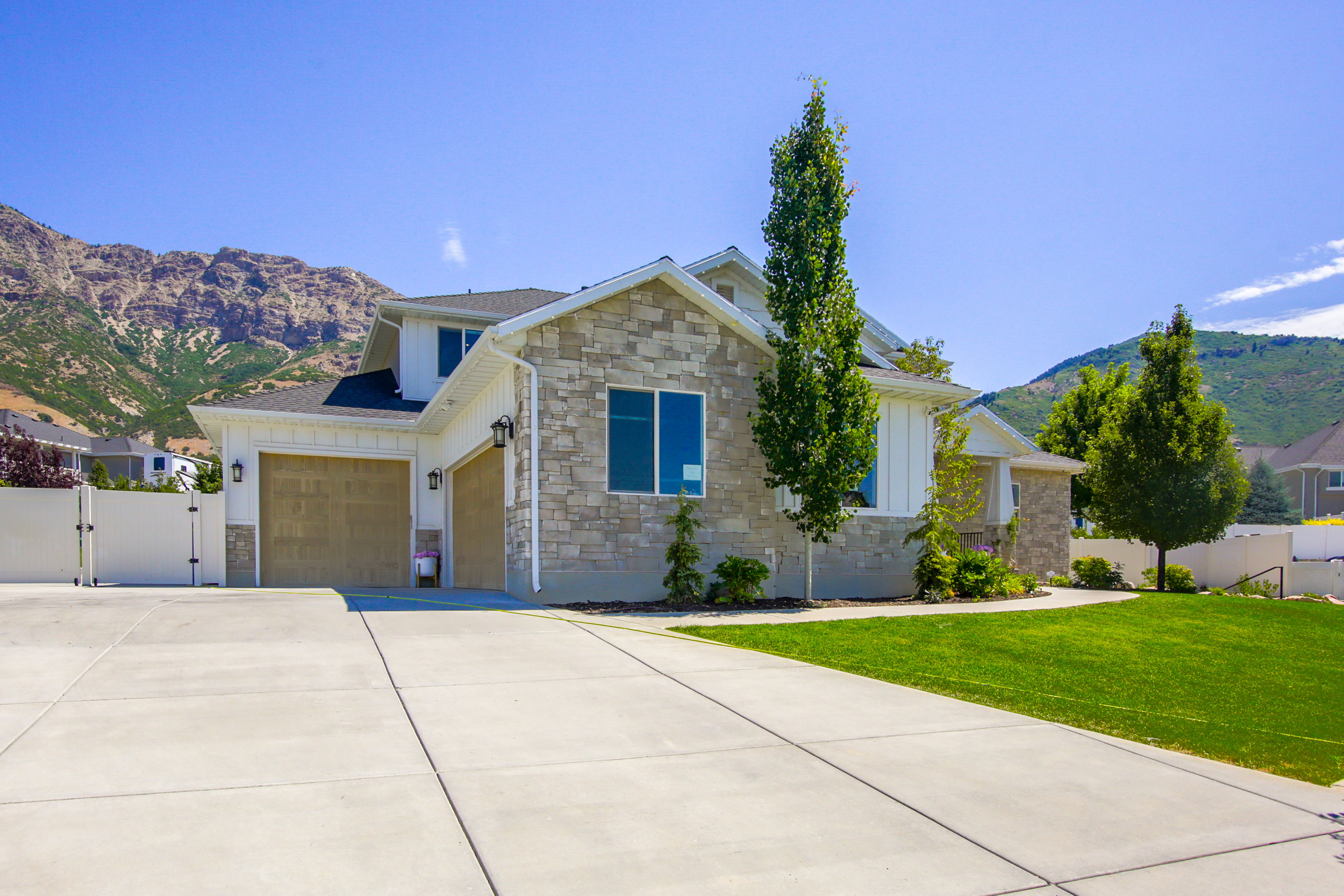 Contemporary home with a stone and siding exterior, featuring a two-car garage with wood-finish doors