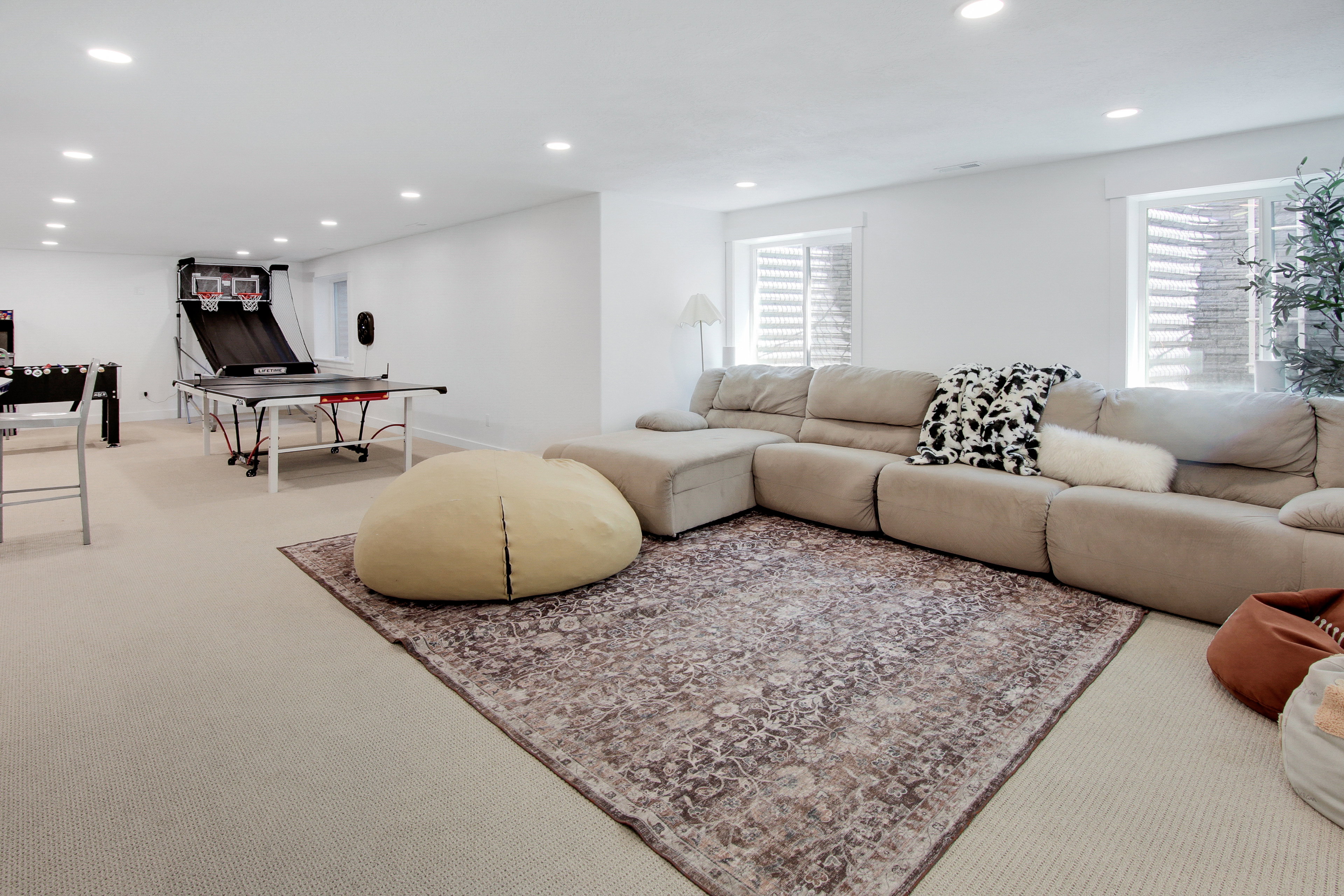 Spacious lower-level entertainment area featuring recessed lighting, light-toned carpeting, and a large area rug