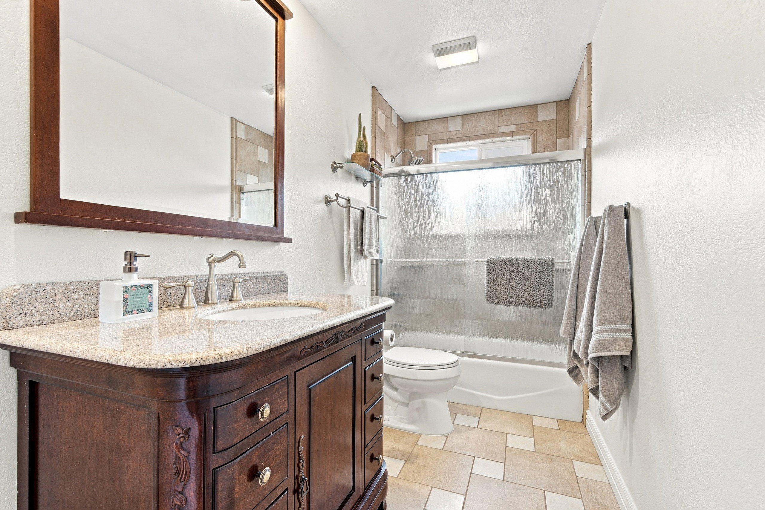 Bathroom featuring a wood vanity with a stone countertop, an undermount sink, and a framed mirror