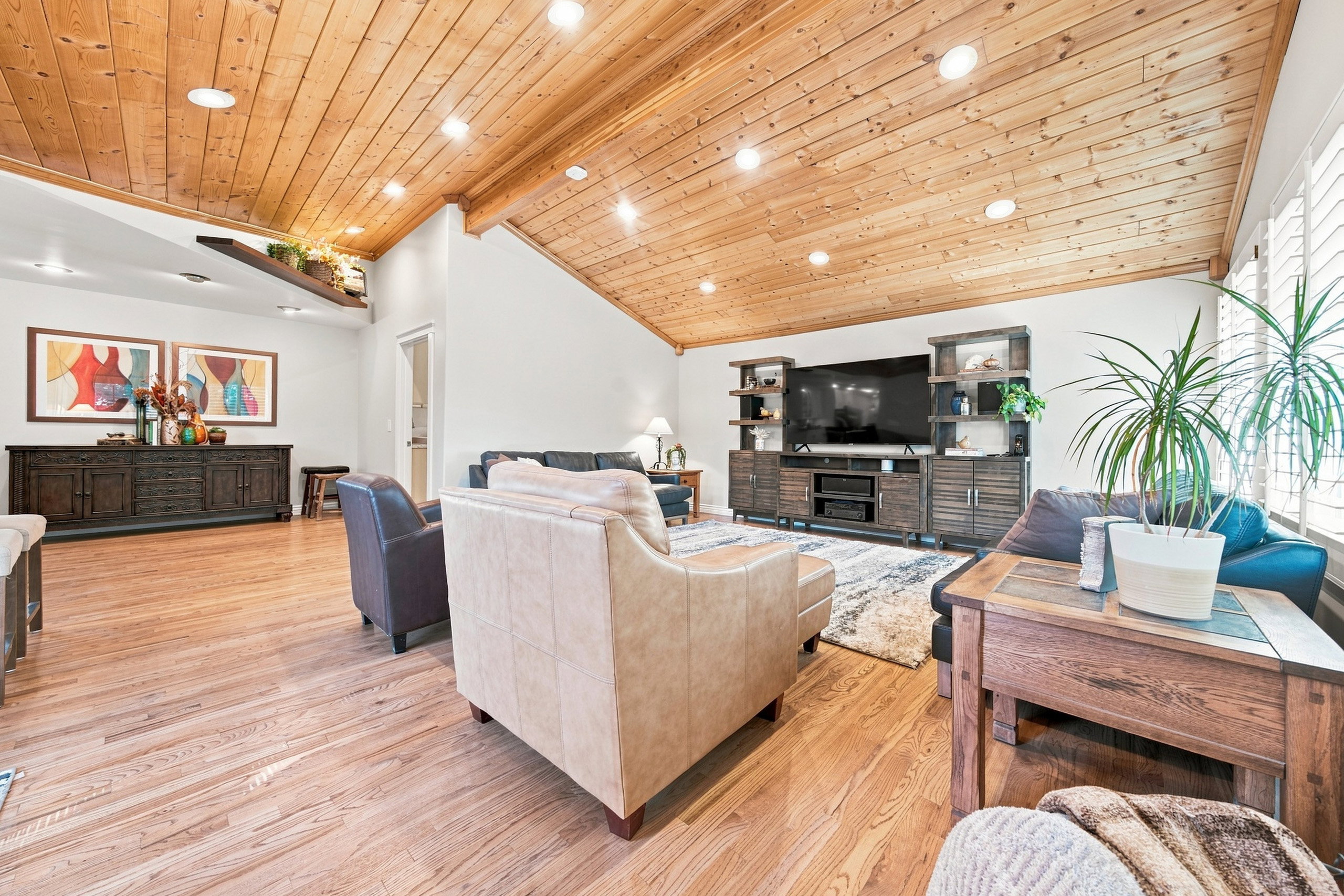 Spacious living area featuring a vaulted wood-plank ceiling with recessed lighting, wood-finish flooring, white walls, and built-in media cabinetry
