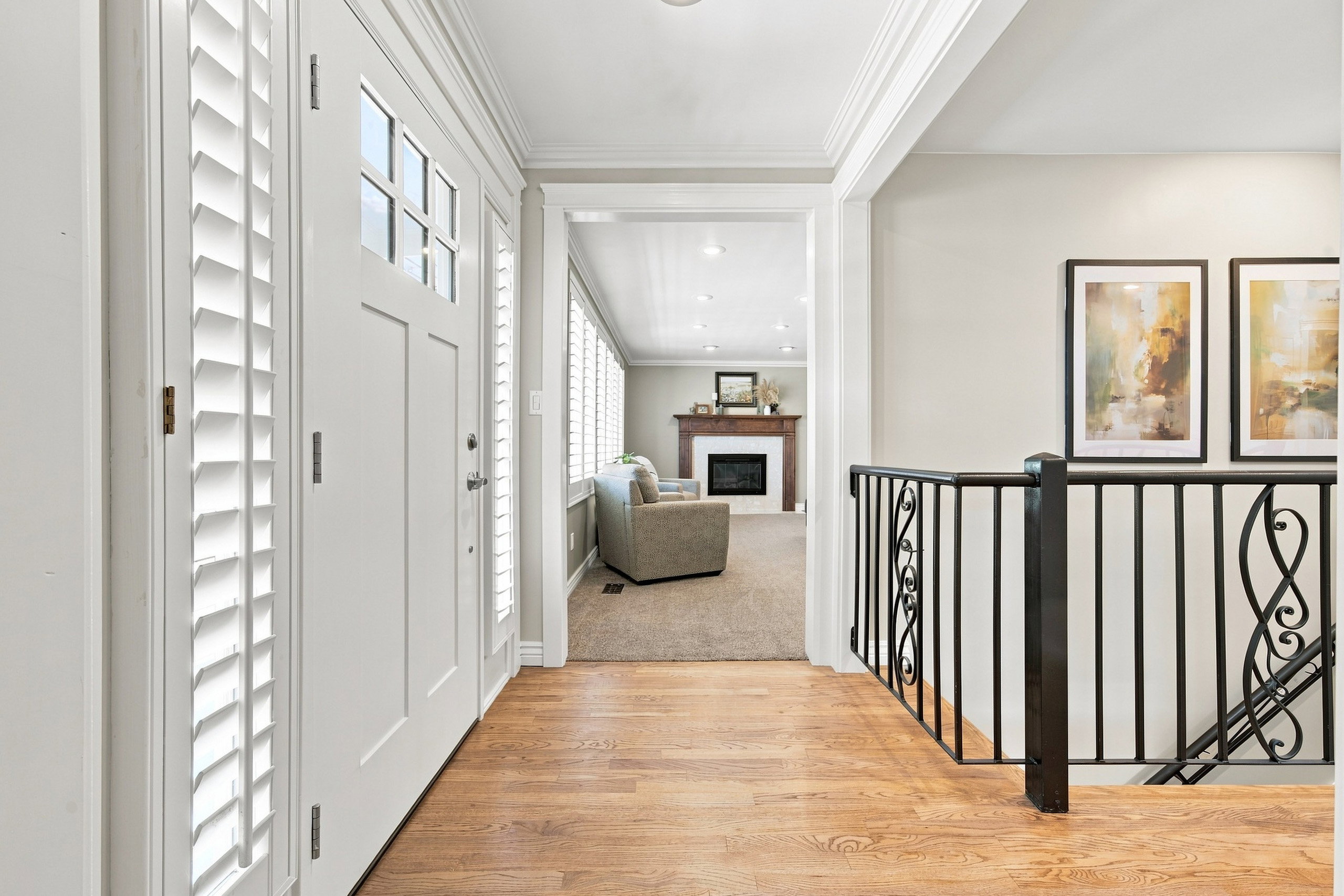 Entryway featuring wood-finish flooring, a white paneled door with glass inserts, and white plantation shutters