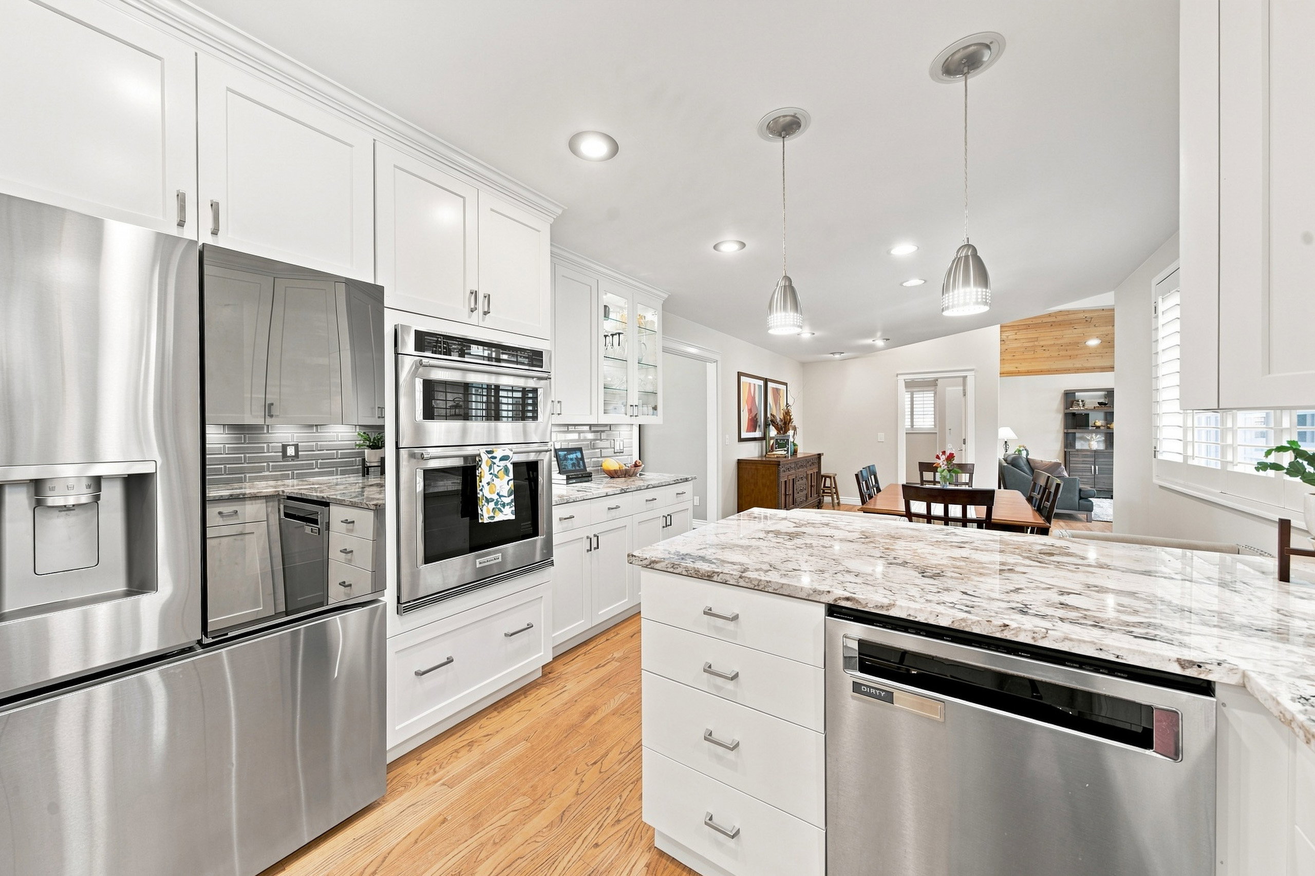 Spacious kitchen featuring white cabinetry, stainless steel appliances, granite countertops, wood-finish flooring, and recessed lighting