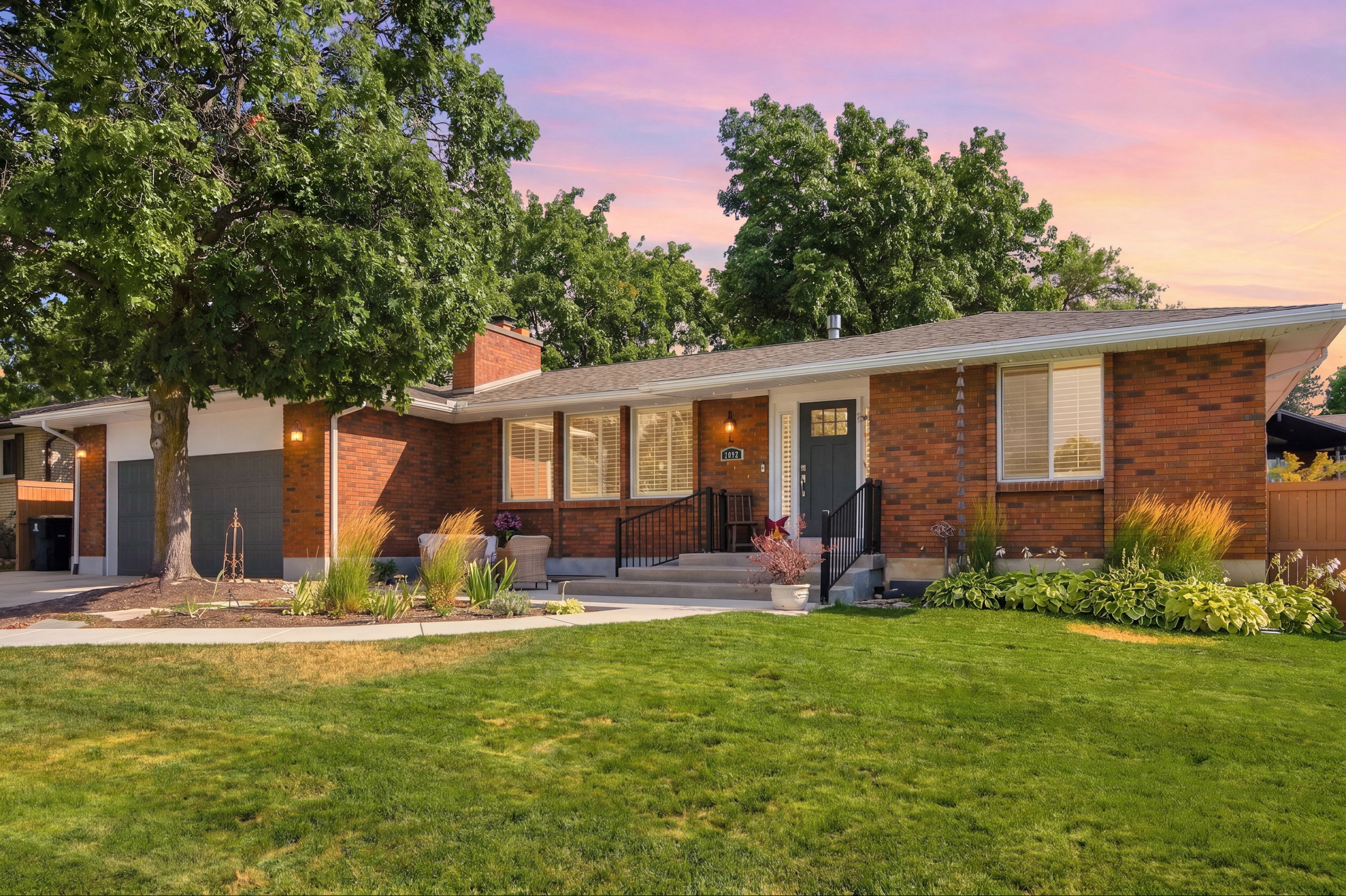 Brick exterior with a detached two-car garage, mature trees, and a landscaped front yard
