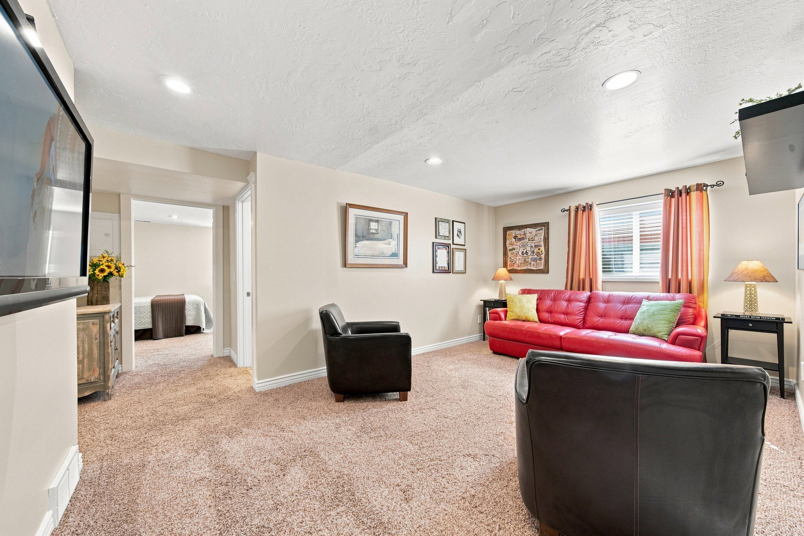 Recessed lighting illuminates this carpeted living space, featuring neutral wall tones and white trim