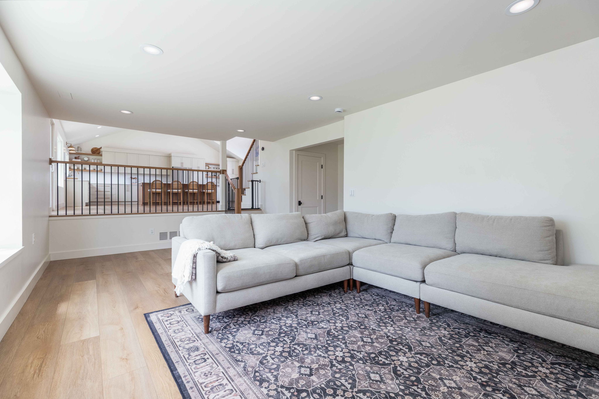 Lower-level living area featuring wood-finish flooring, recessed lighting, and a white color palette