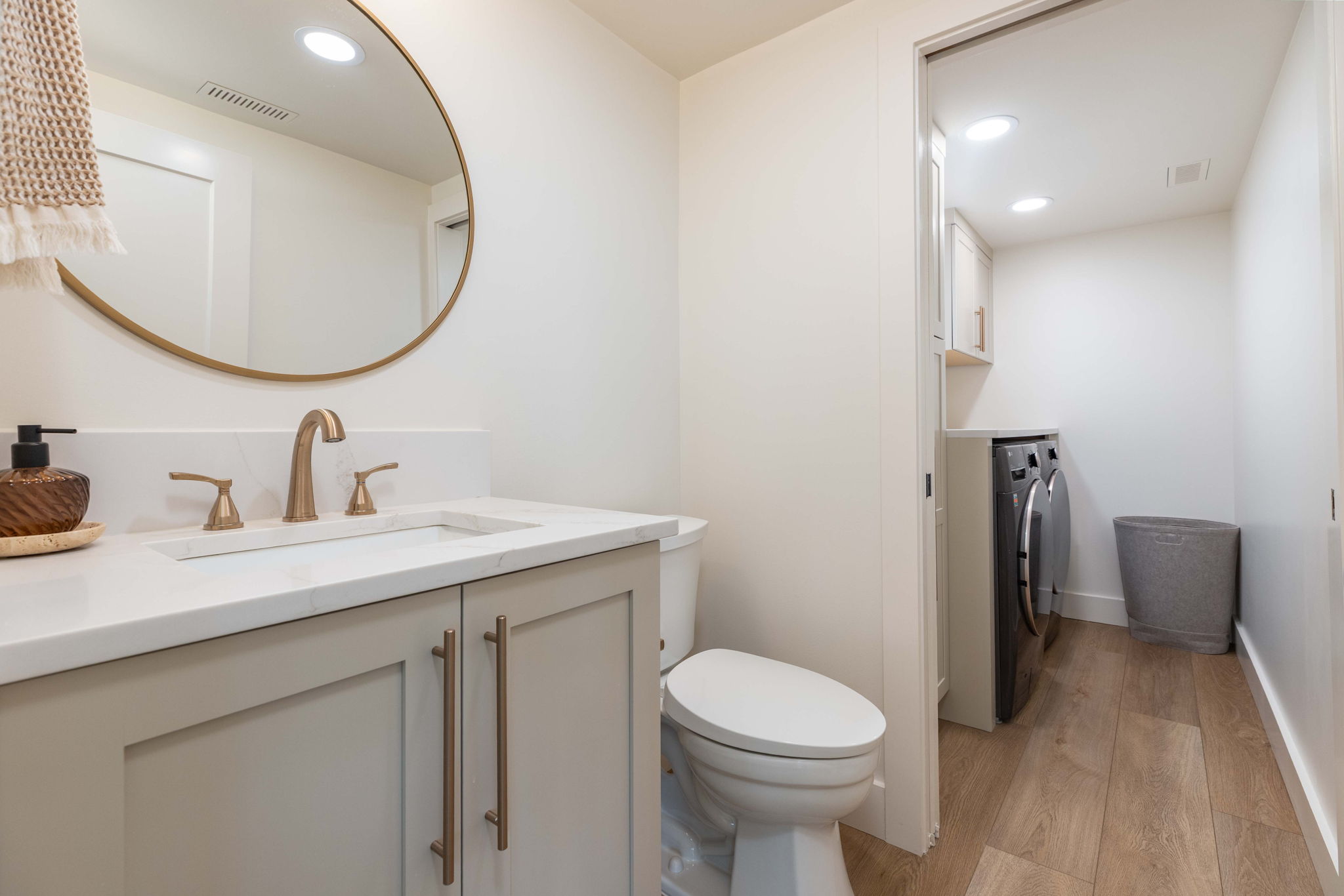 Bathroom vanity featuring a rectangular undermount sink, a bronze-finish faucet, and a light gray cabinet with bronze hardware