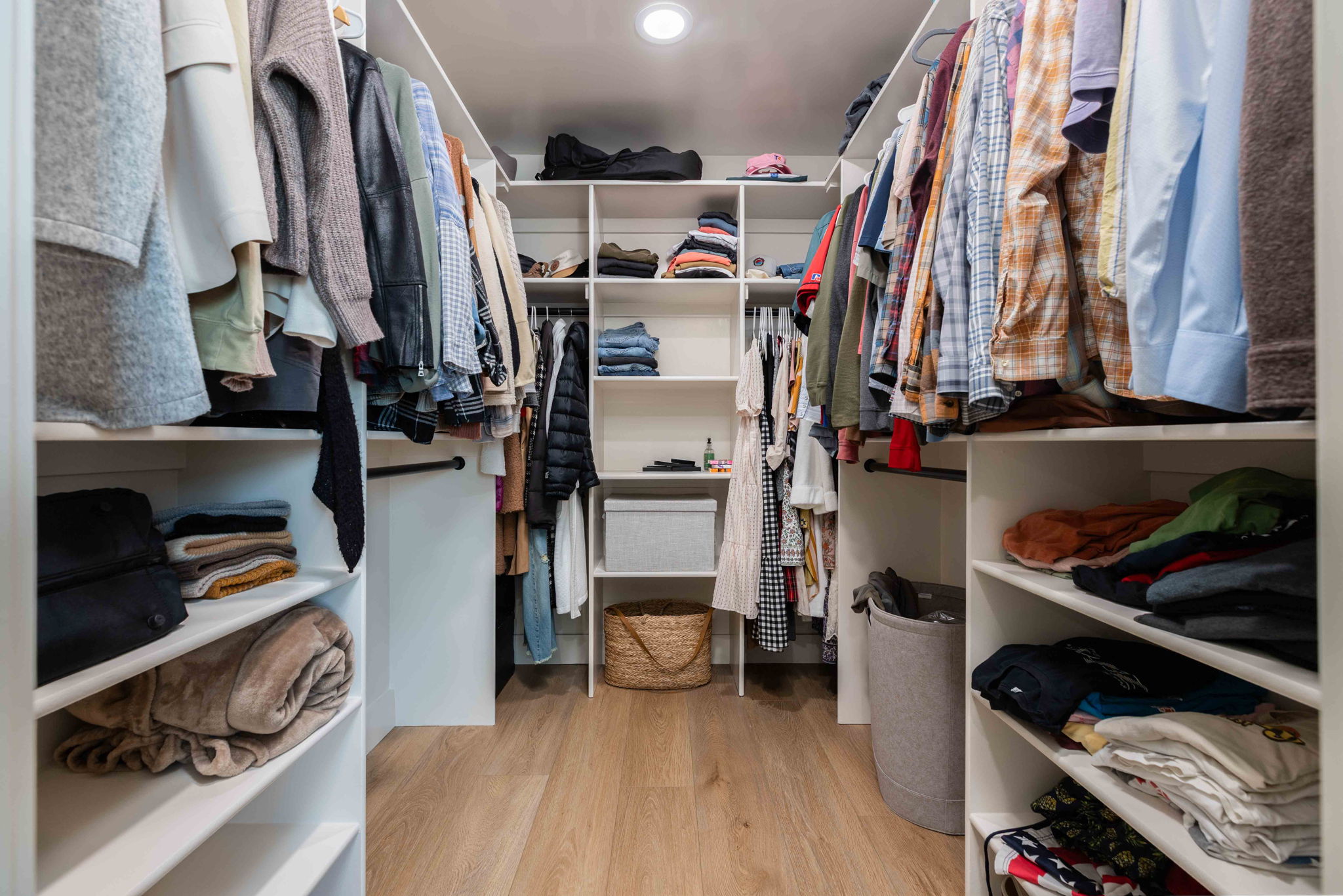 Walk-in closet featuring built-in white shelving, multiple hanging rods, recessed lighting, and wood-finish flooring