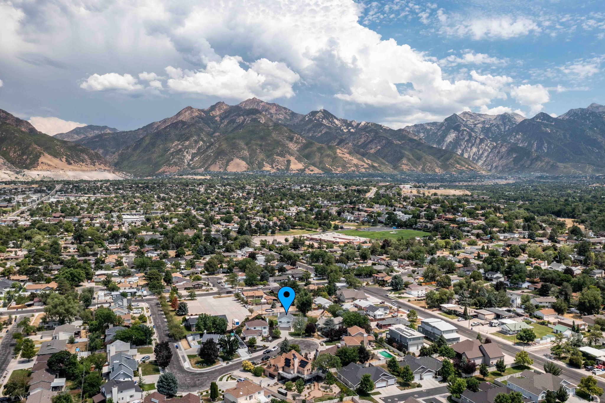 Expansive aerial perspective showcasing a residential neighborhood with abundant mature trees and mountainous terrain